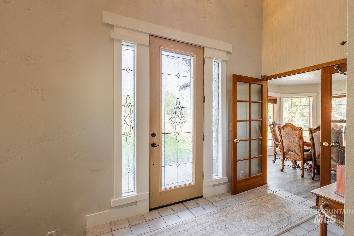 Entrance foyer with plenty of natural light, french doors, a textured wall, and light tile patterned flooring