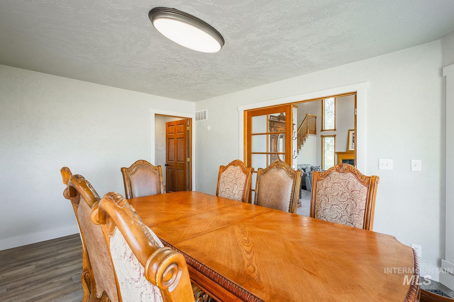 Dining space featuring a textured ceiling, stairs, and dark wood finished floors
