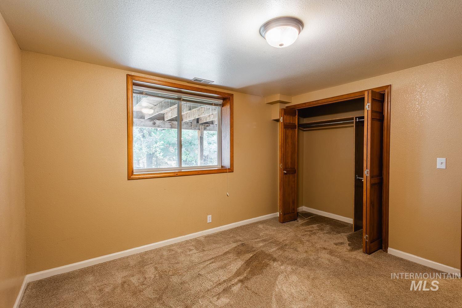 Unfurnished bedroom featuring carpet, a closet, a textured ceiling, and a textured wall