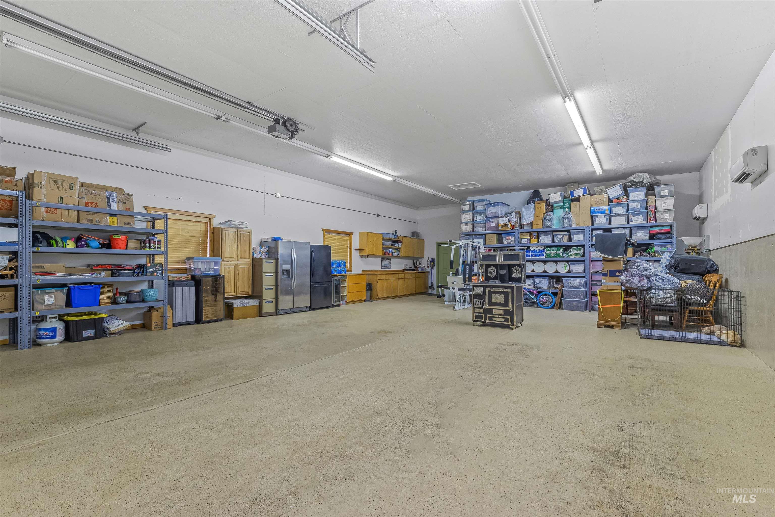 Garage featuring freestanding refrigerator and stainless steel refrigerator with ice dispenser