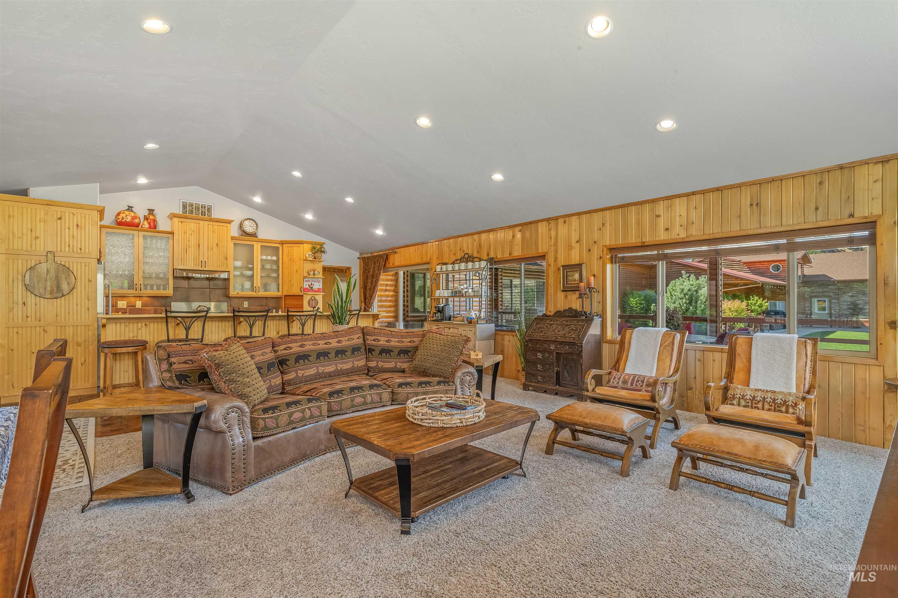 Living room featuring vaulted ceiling, wooden walls, light carpet, and recessed lighting