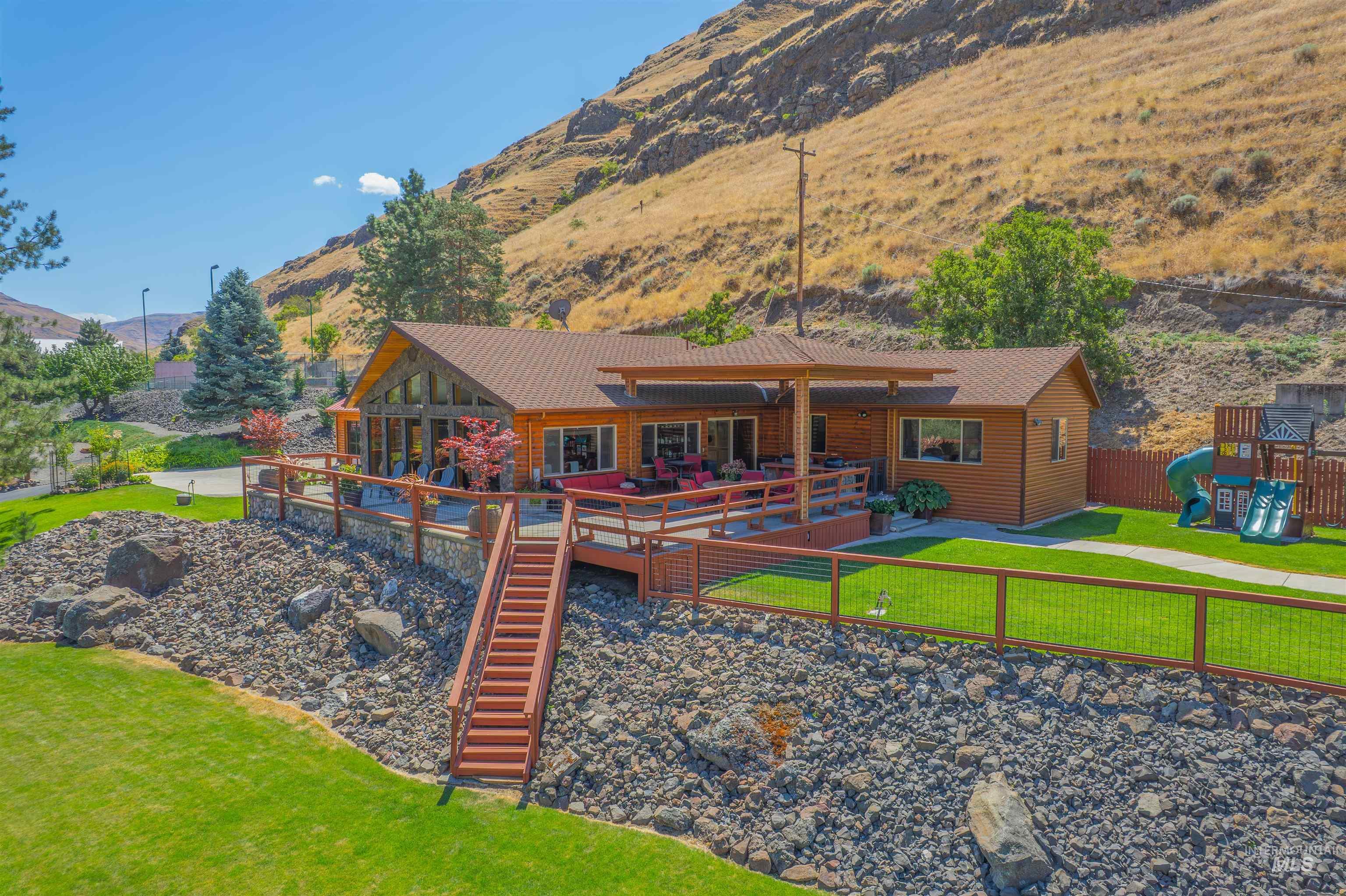 Back of property featuring a deck with mountain view and a playground