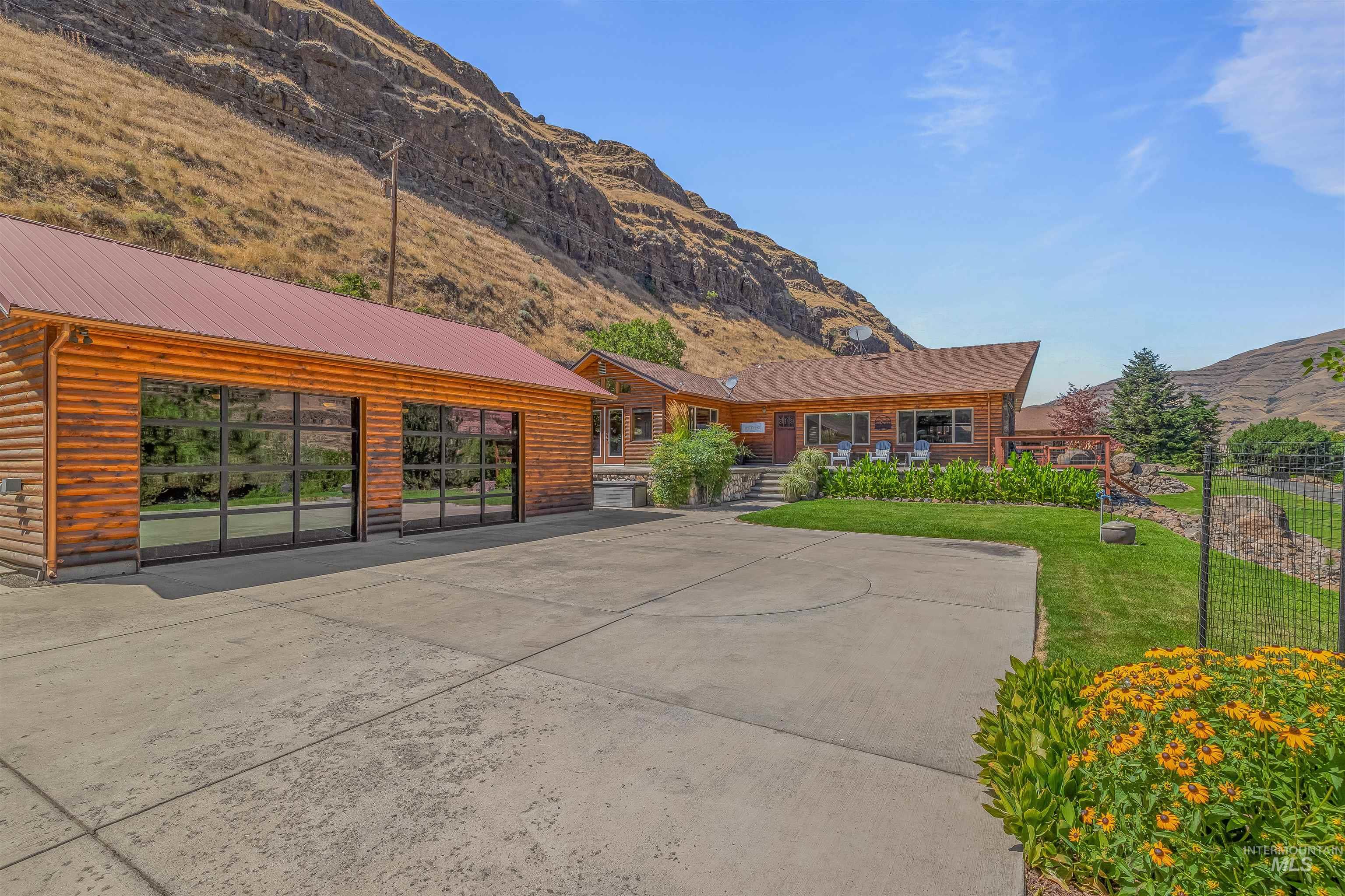 View of front facade featuring a mountain view, faux log siding, a metal roof, and a front lawn