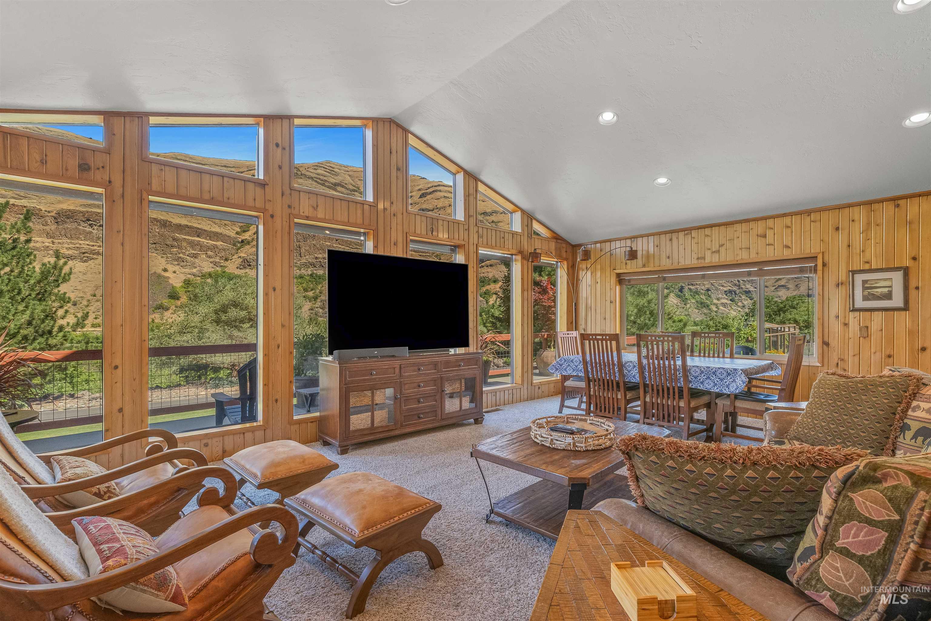 Carpeted living area with wood walls, vaulted ceiling, and recessed lighting