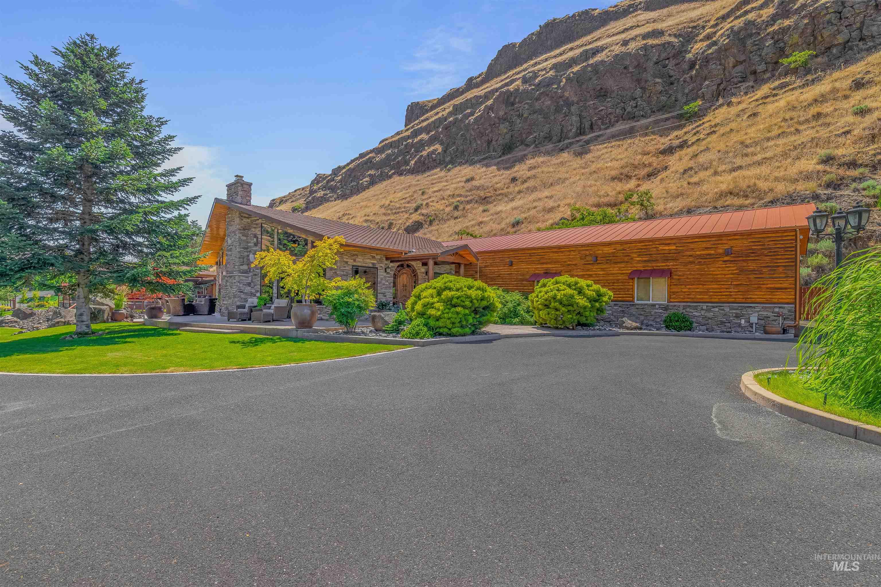 View of front of home with stone siding, a mountain view, a chimney, and a metal roof