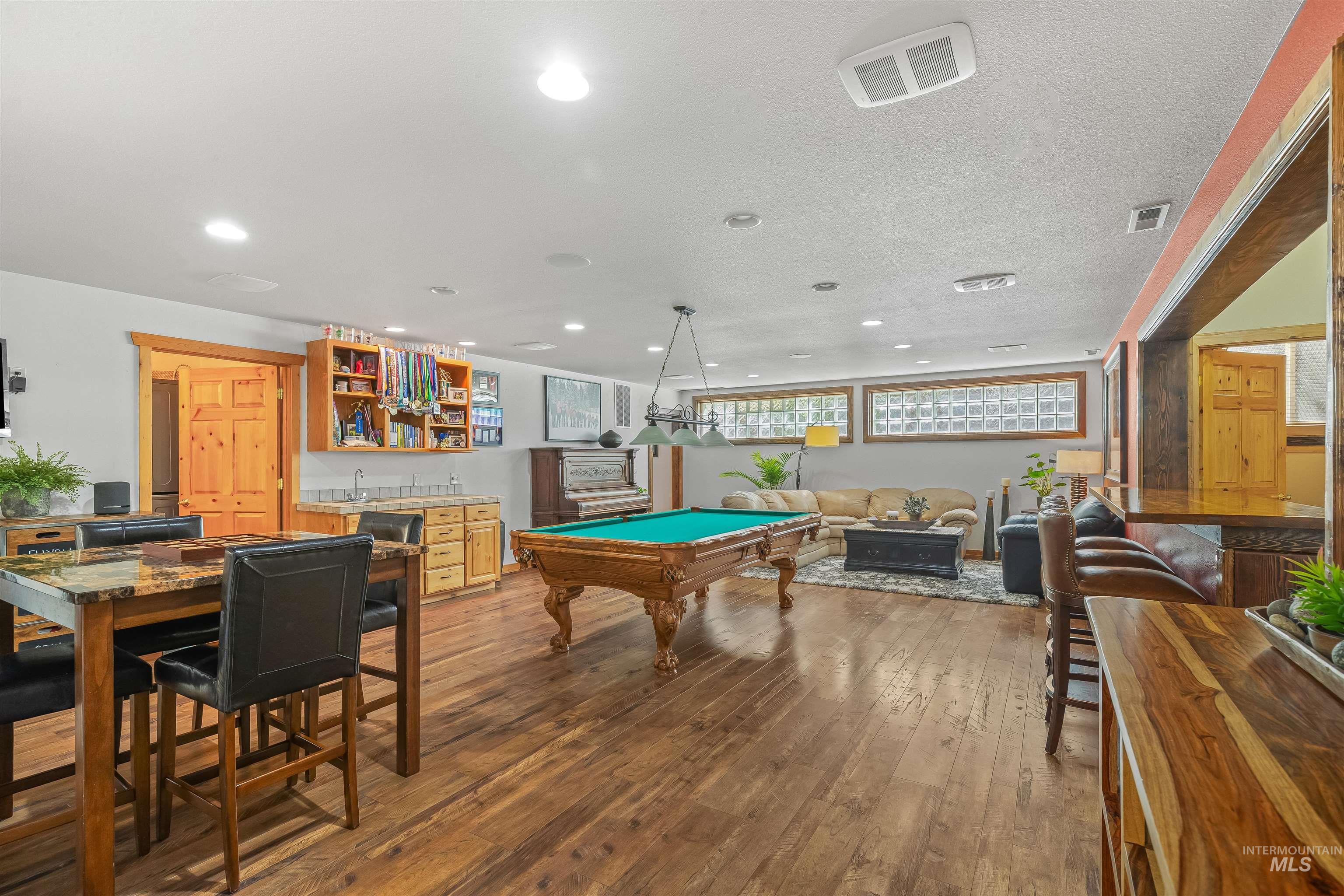 Playroom featuring wet bar, recessed lighting, hardwood / wood-style floors, pool table, and a textured ceiling