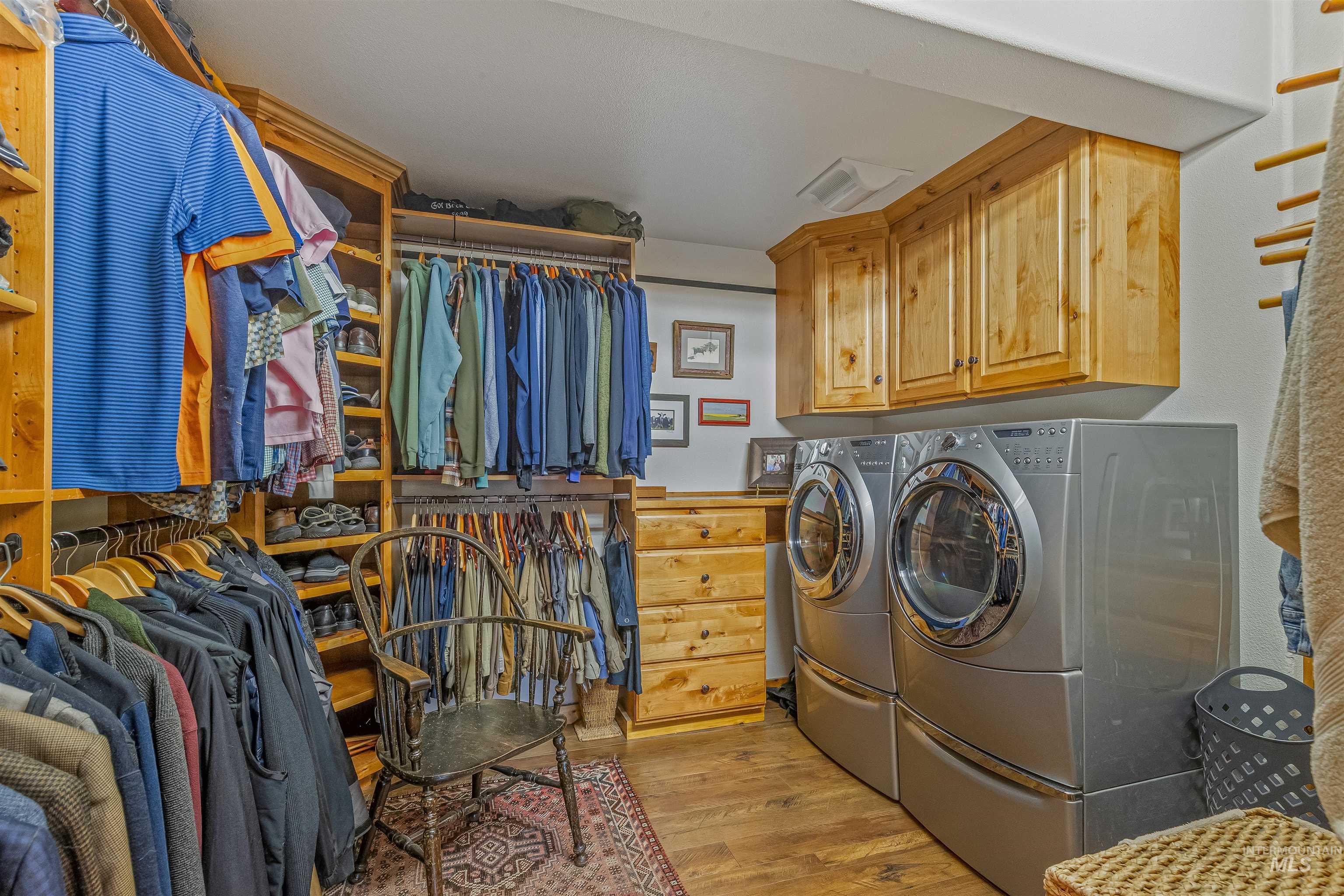 Washroom with cabinet space, washing machine and dryer, and light wood-type flooring