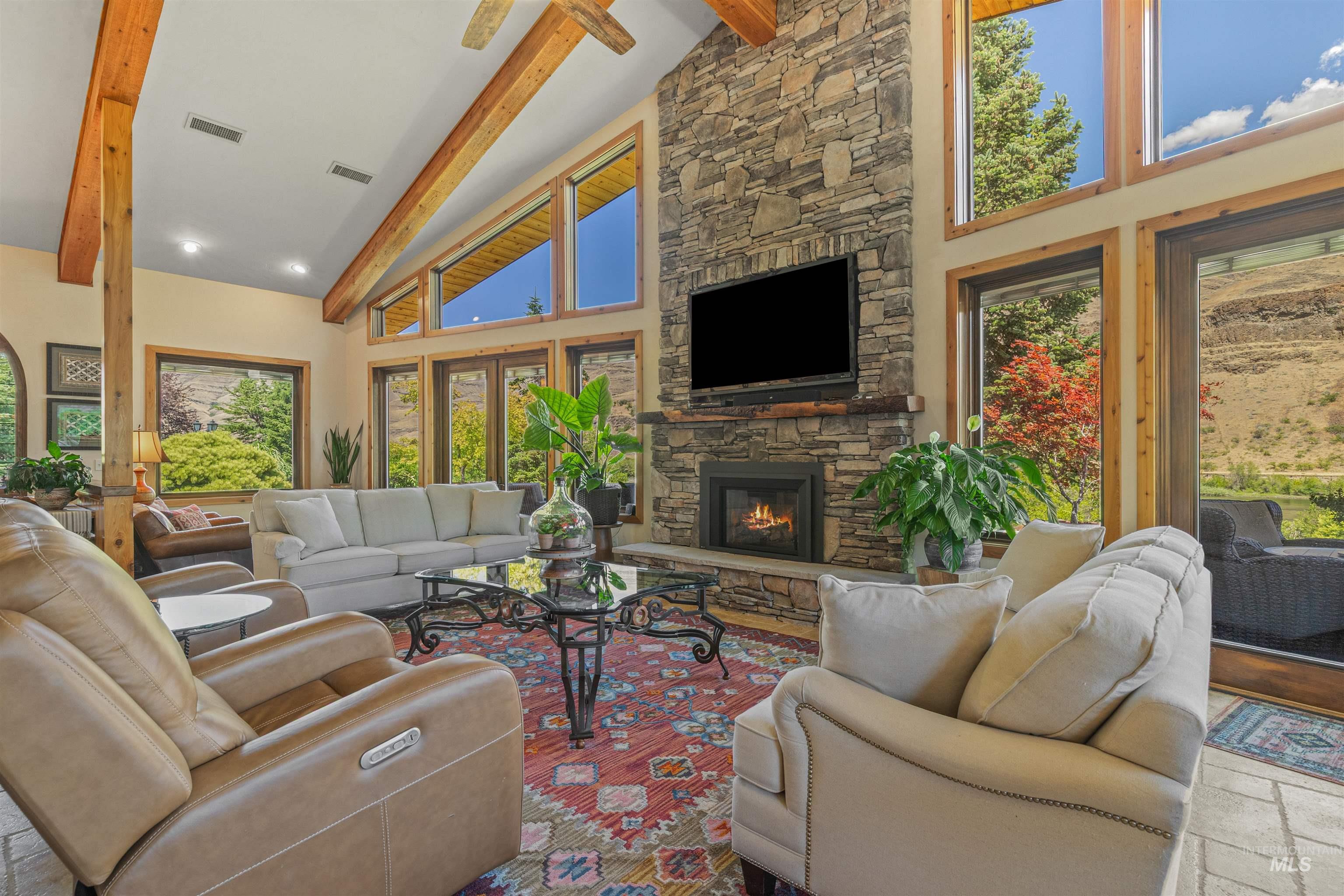 Living room with high vaulted ceiling, beam ceiling, plenty of natural light, and a fireplace