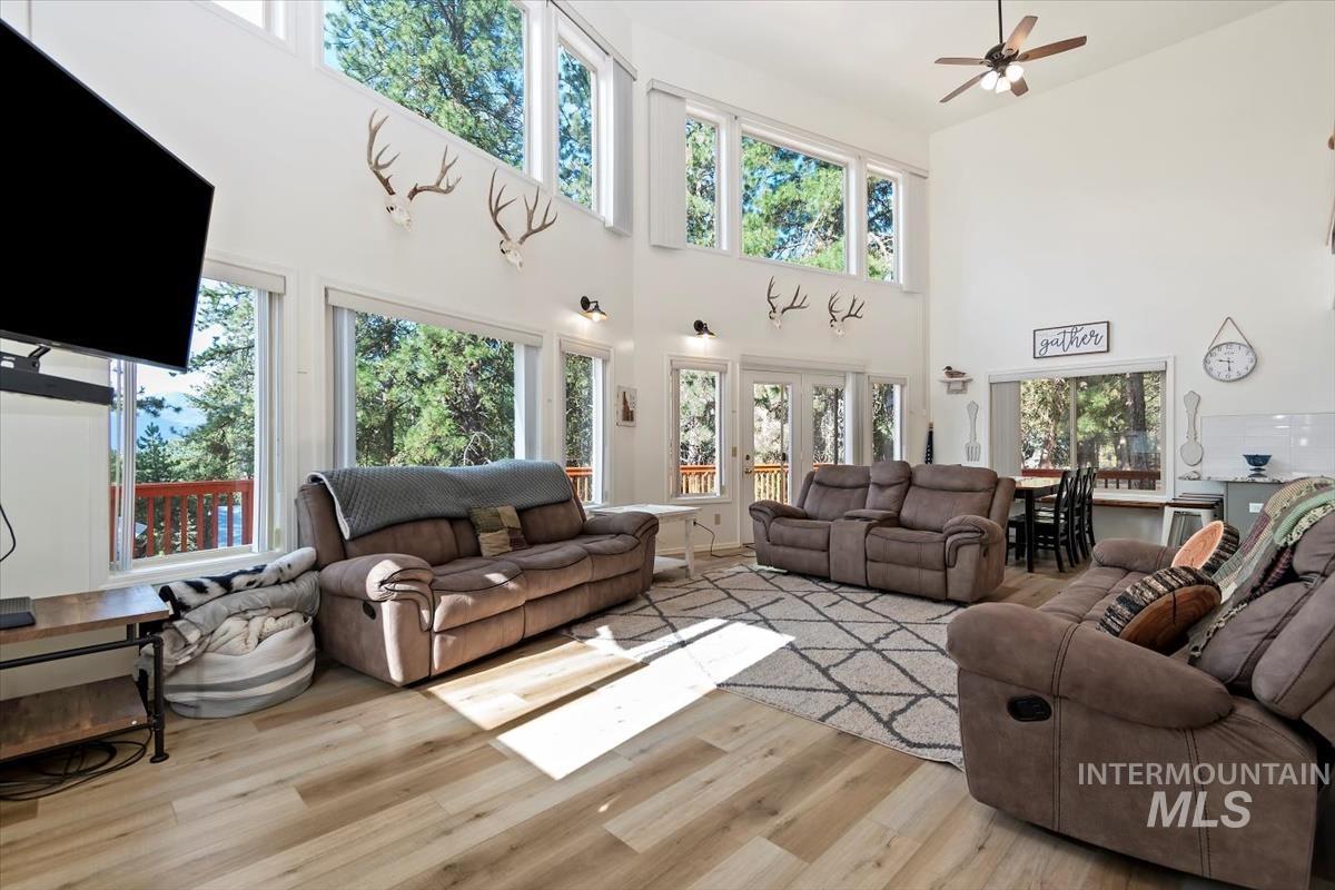 Living area featuring a towering ceiling, light wood finished floors, a ceiling fan, and french doors
