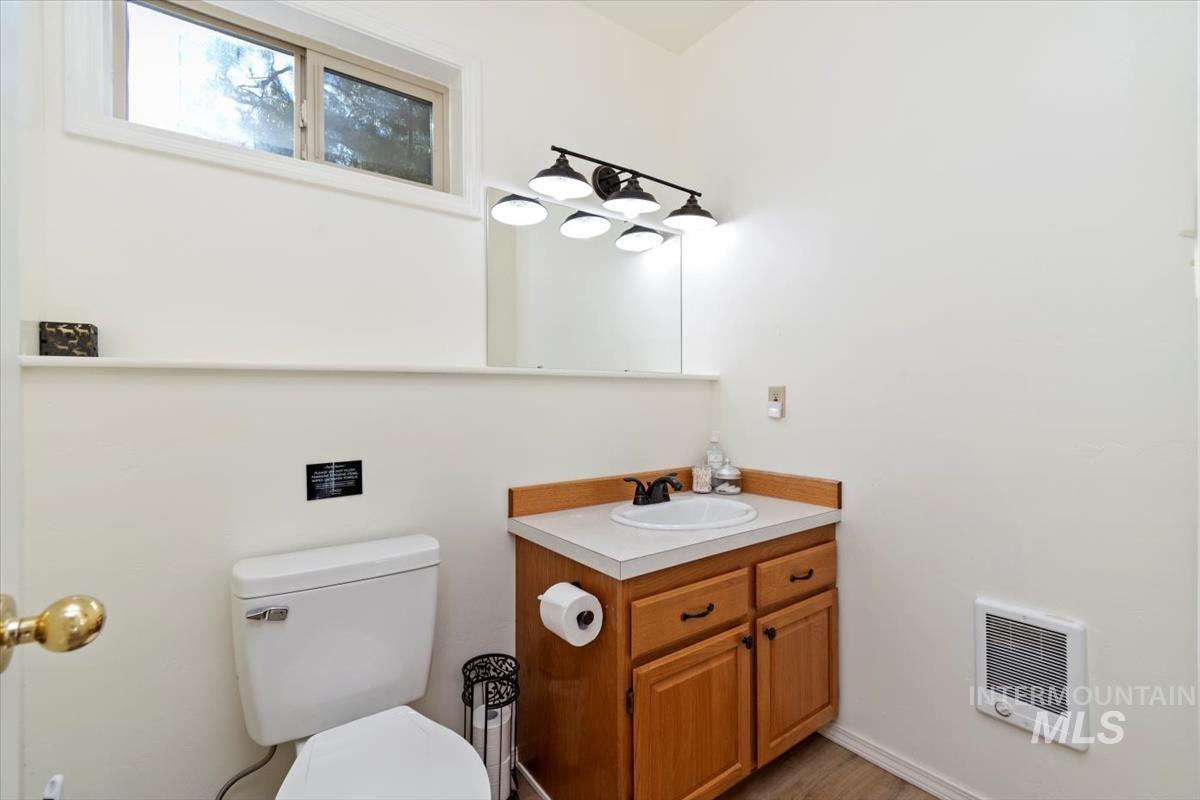Half bath featuring vanity, heating unit, and light wood-style floors