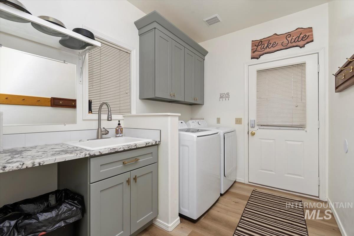 Washroom with light wood-type flooring, separate washer and dryer, and cabinet space