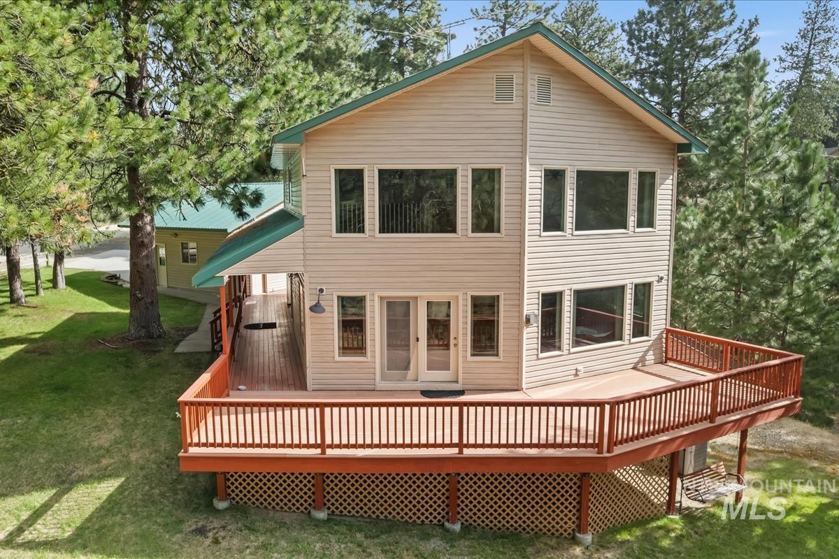 Rear view of house with a wooden deck and a lawn