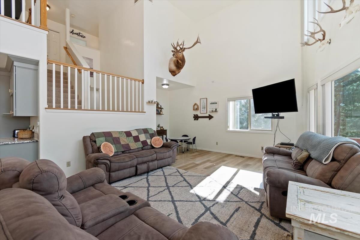 Living area with a towering ceiling, wood finished floors, and stairway
