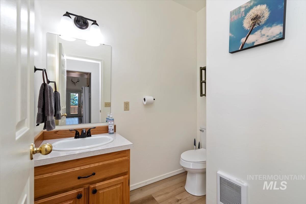 Half bathroom featuring vanity, light wood-type flooring, and heating unit