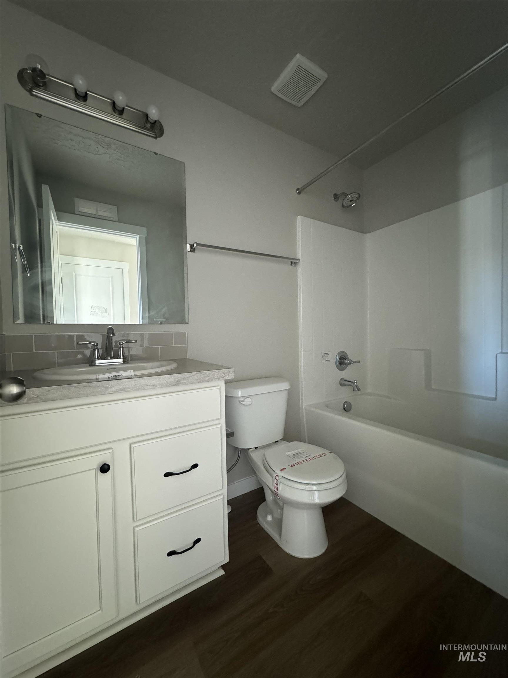 Full bathroom with dark wood finished floors, vanity, and shower / bath combination
