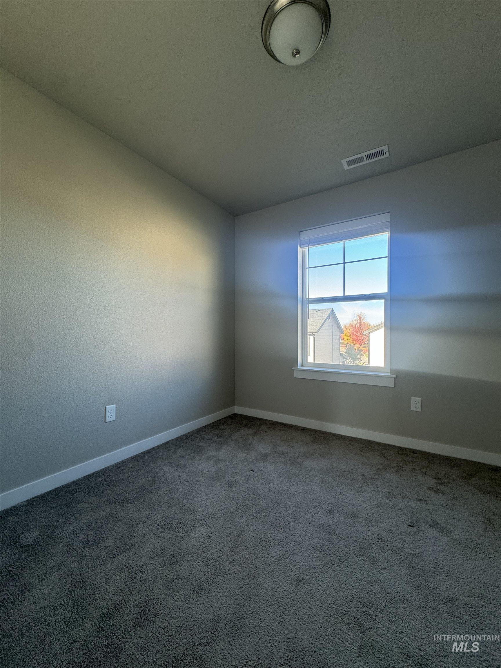 Empty room featuring carpet flooring and a textured ceiling