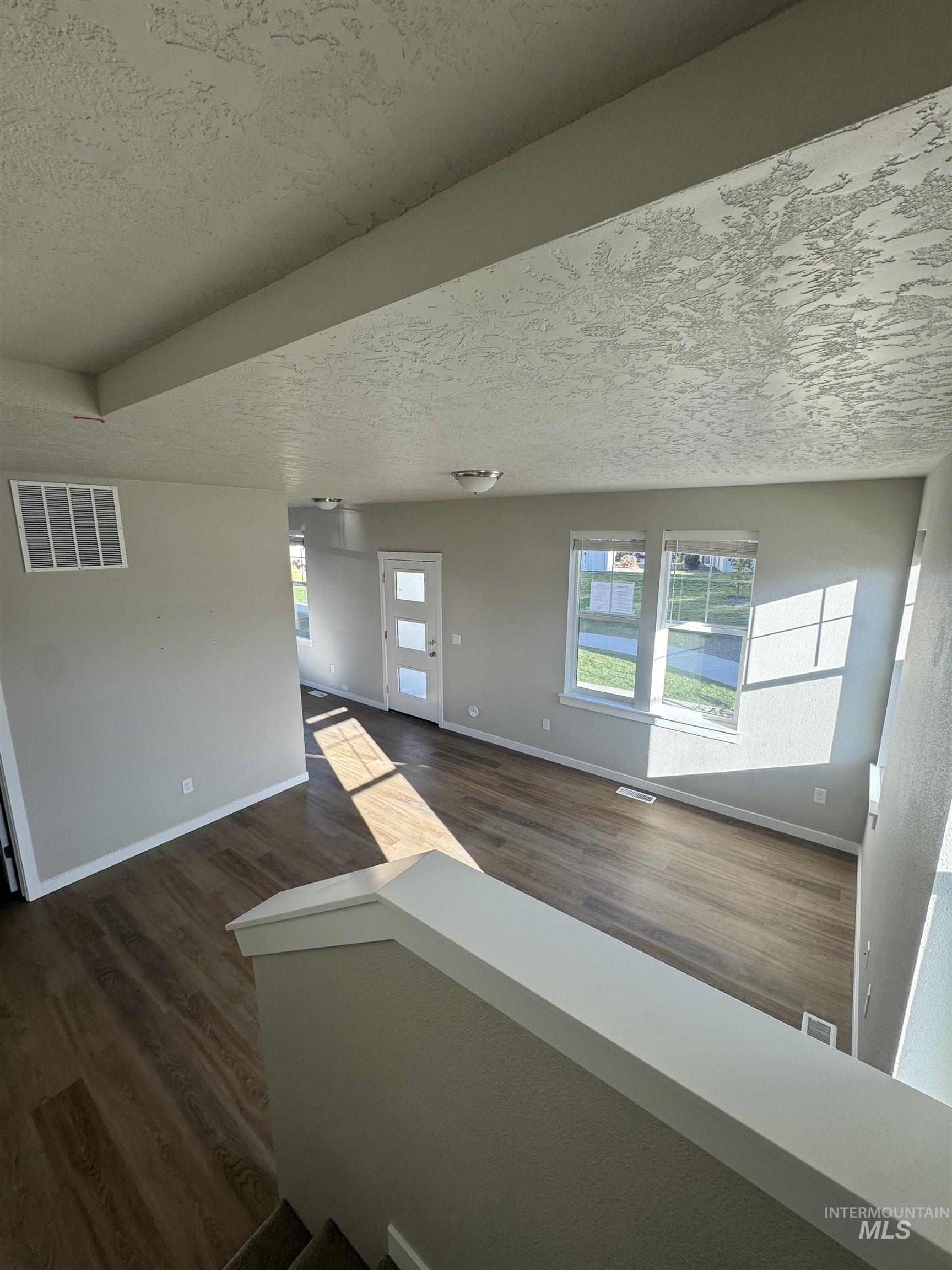 Unfurnished room featuring a textured ceiling and dark wood-type flooring