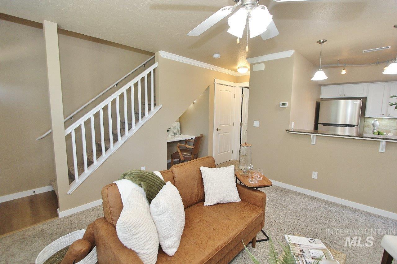 Open-concept living area with neutral carpeting and a ceiling fan
