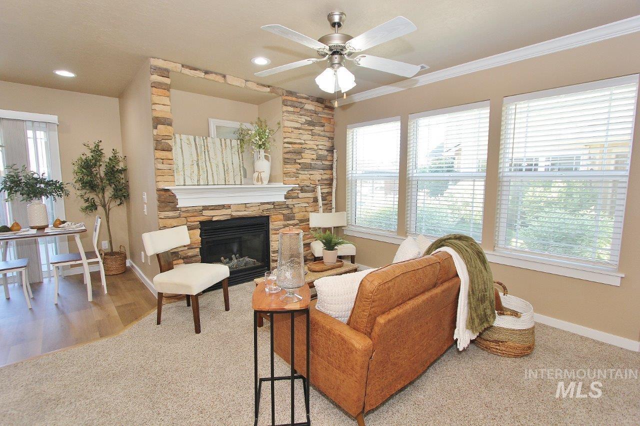 Living area featuring a stacked stone fireplace with a white mantel, recessed lighting, and a ceiling fan