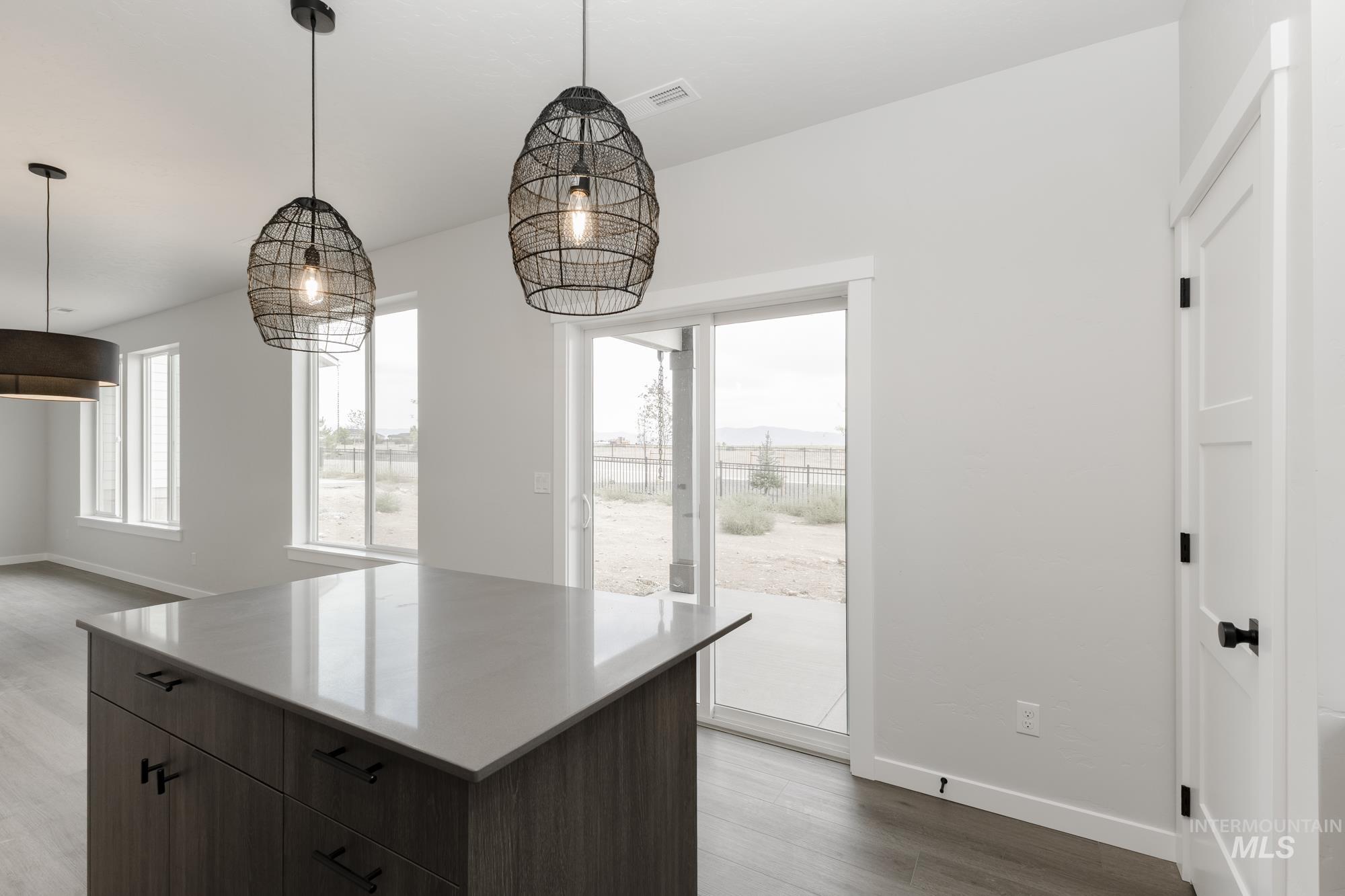 Kitchen with dark brown cabinets, decorative light fixtures, plenty of natural light, and light wood finished floors