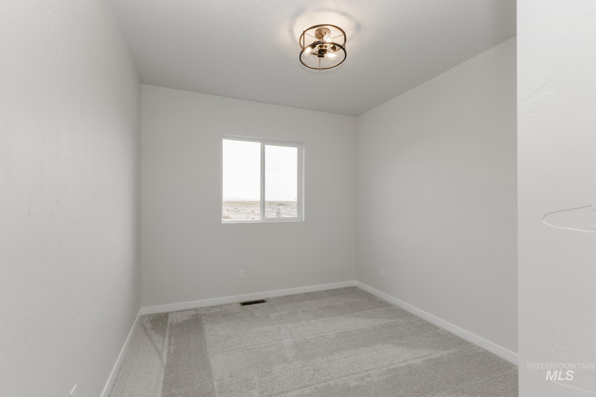 Spare room featuring light carpet and baseboards