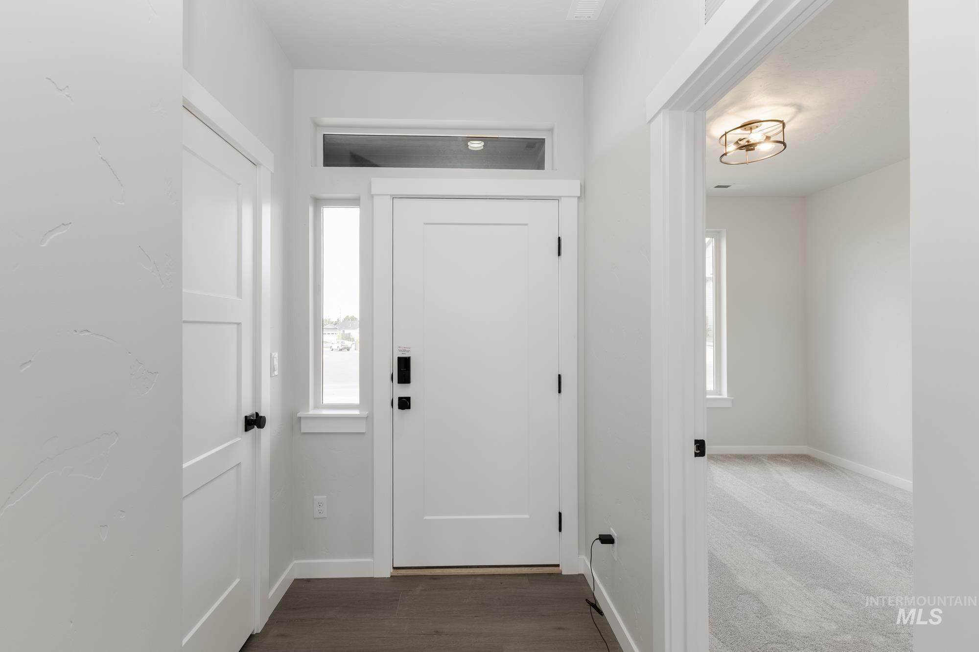 Foyer with dark colored carpet and dark wood-type flooring