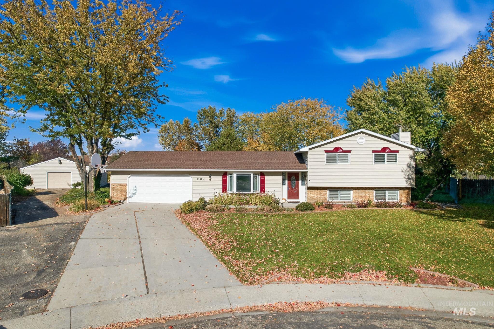Split level home featuring a front yard, brick siding, a chimney, and concrete driveway