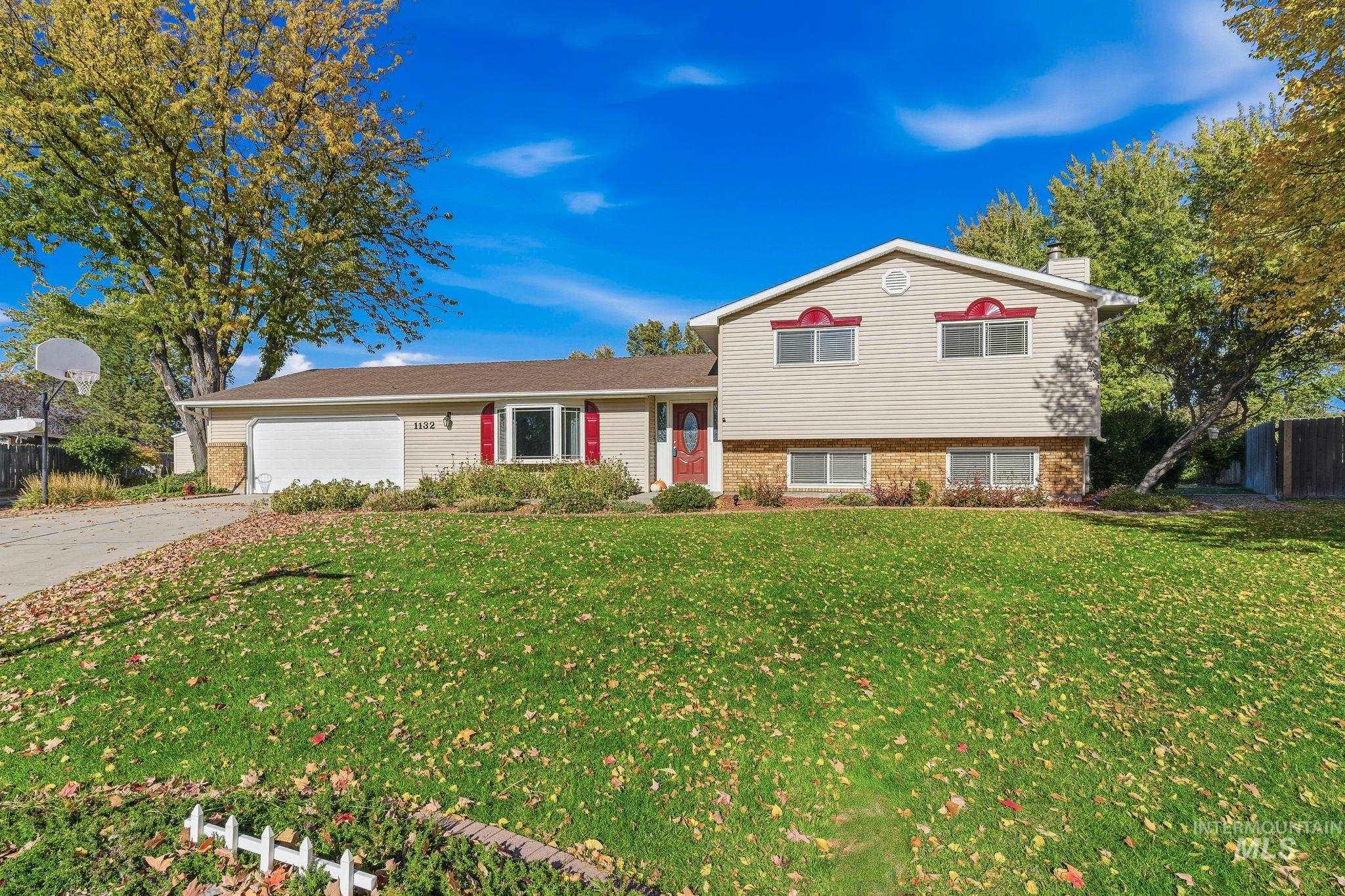 Tri-level home featuring a chimney, concrete driveway, an attached garage, and brick siding