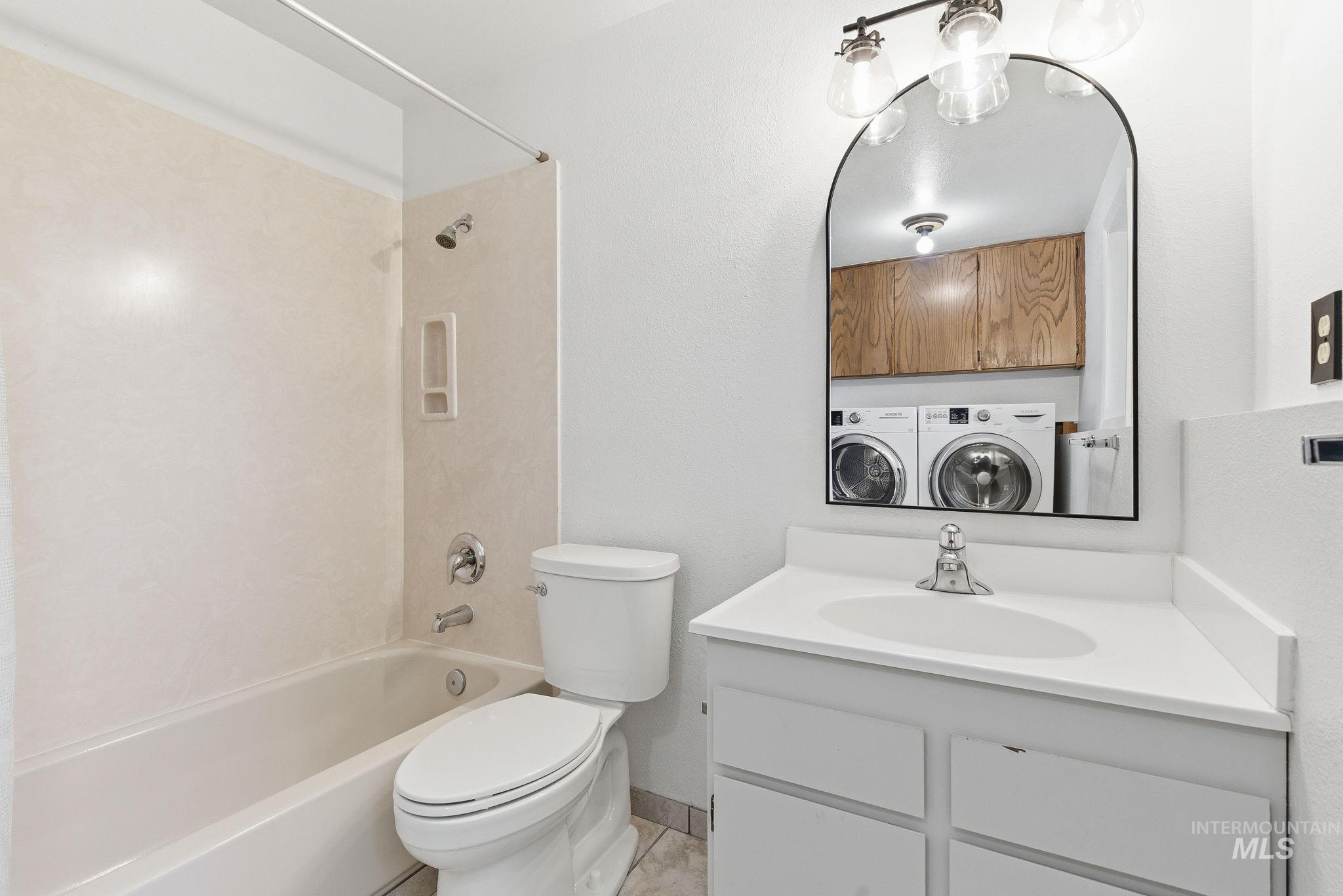 Full bath featuring washing machine and clothes dryer, vanity, and washtub / shower combination