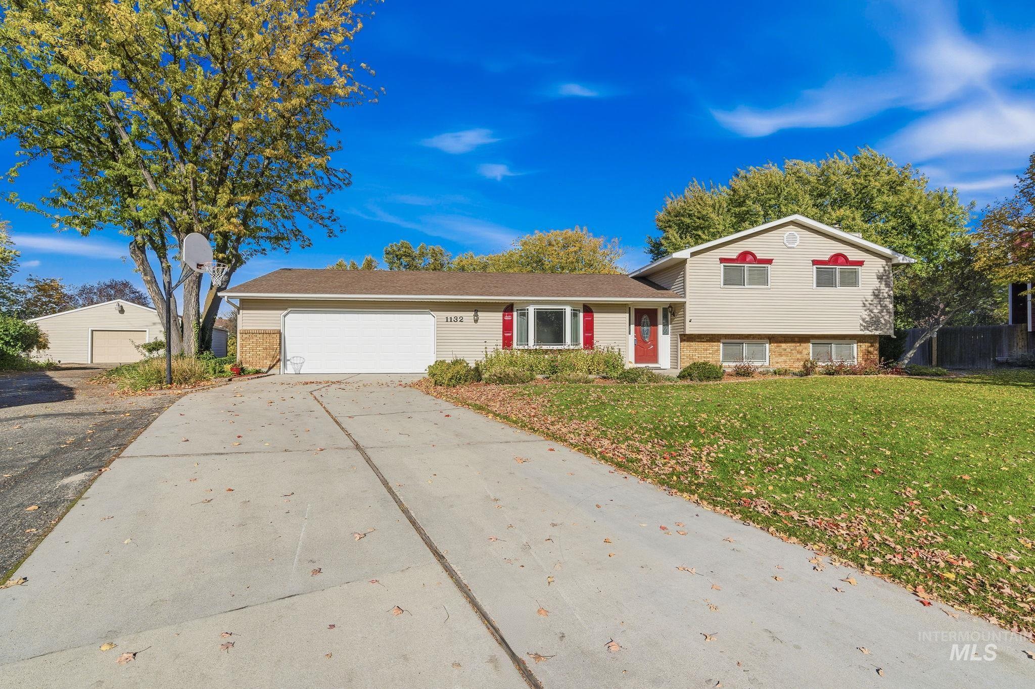 Split level home featuring brick siding, driveway, a front yard, and a garage