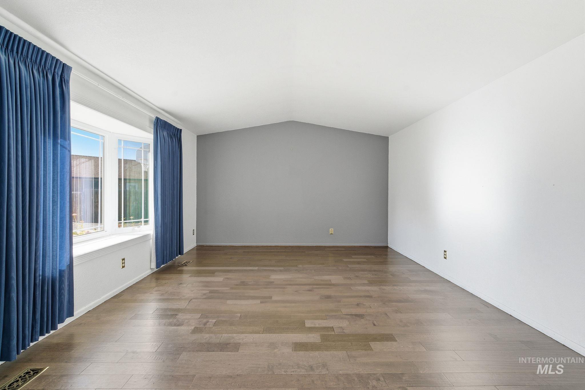 Spare room featuring light wood-type flooring and vaulted ceiling