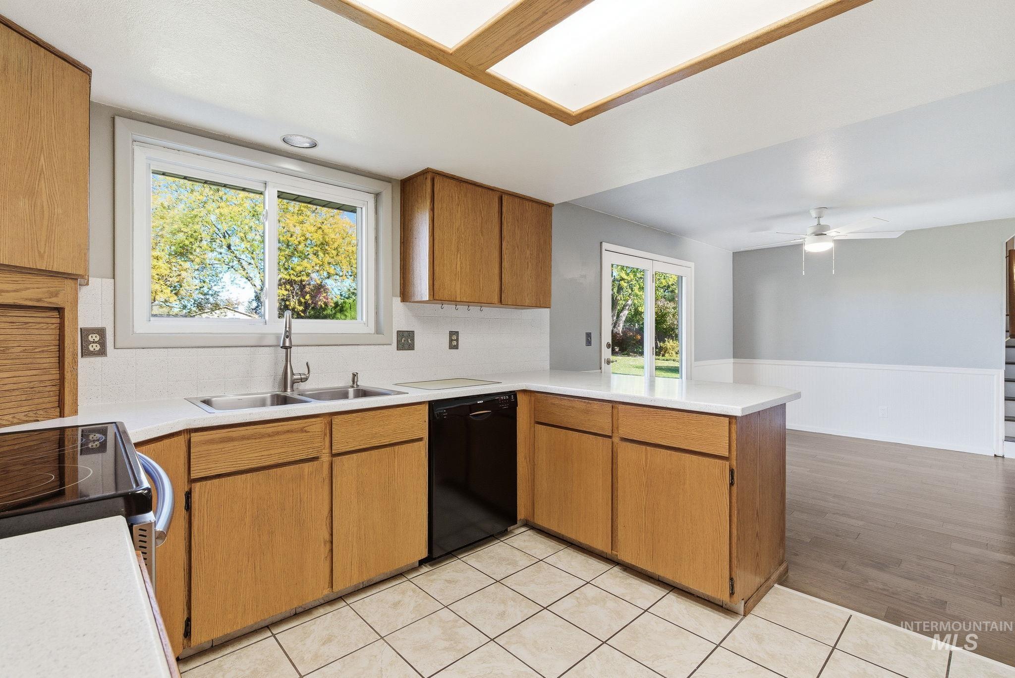 Kitchen featuring brown cabinets, light countertops, wainscoting, and decorative backsplash