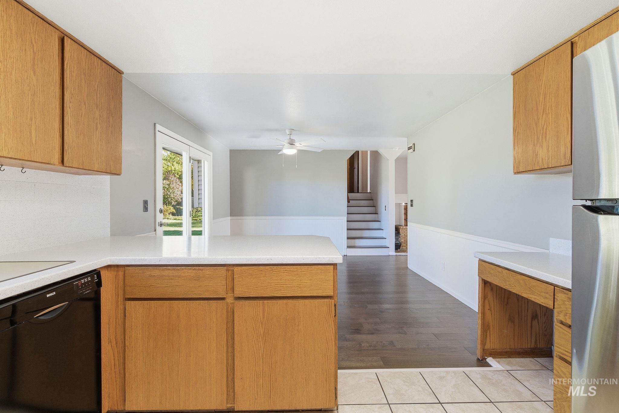 Kitchen with a peninsula, dishwasher, freestanding refrigerator, and brown cabinets