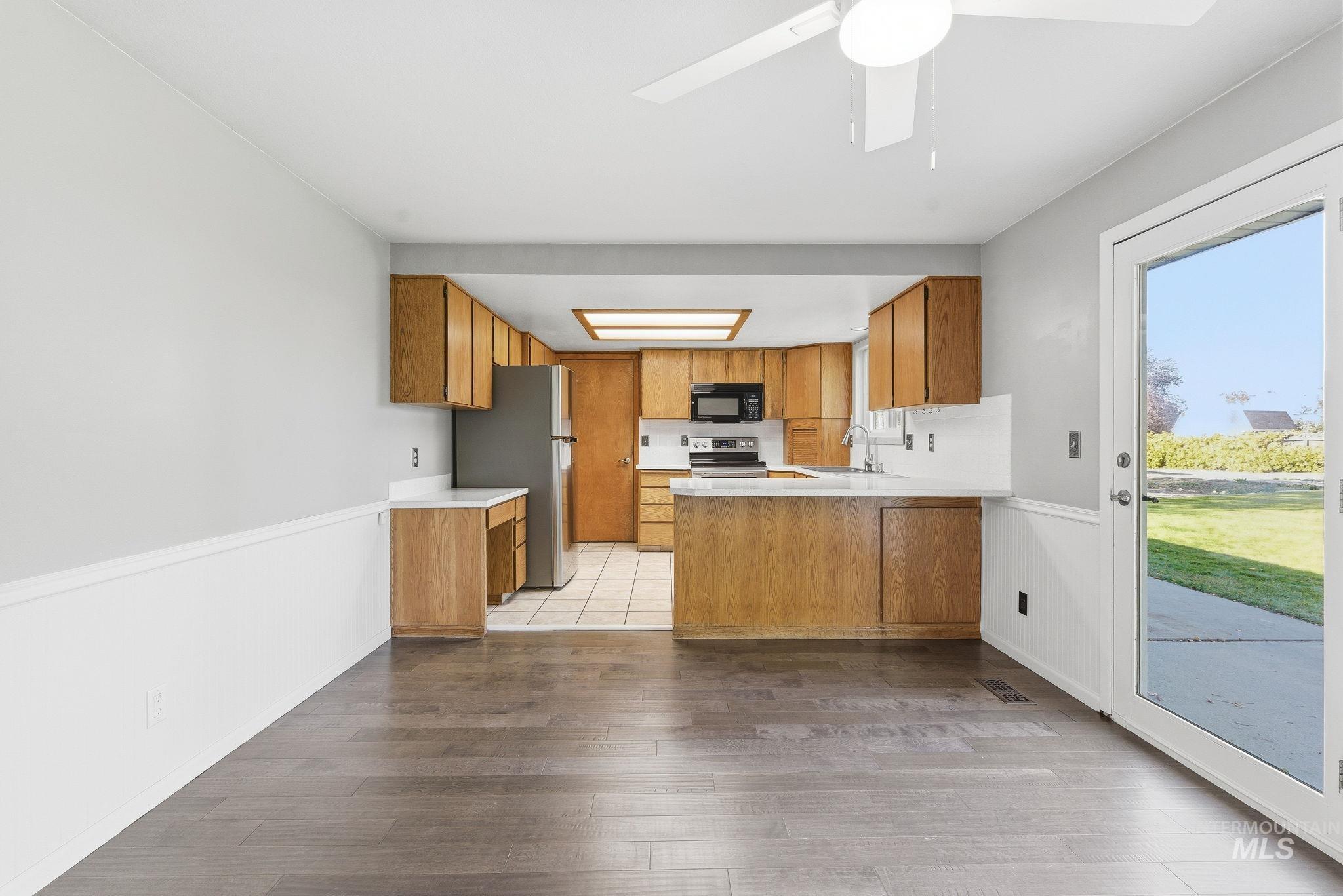 Kitchen with light countertops, a peninsula, brown cabinetry, and light wood-type flooring