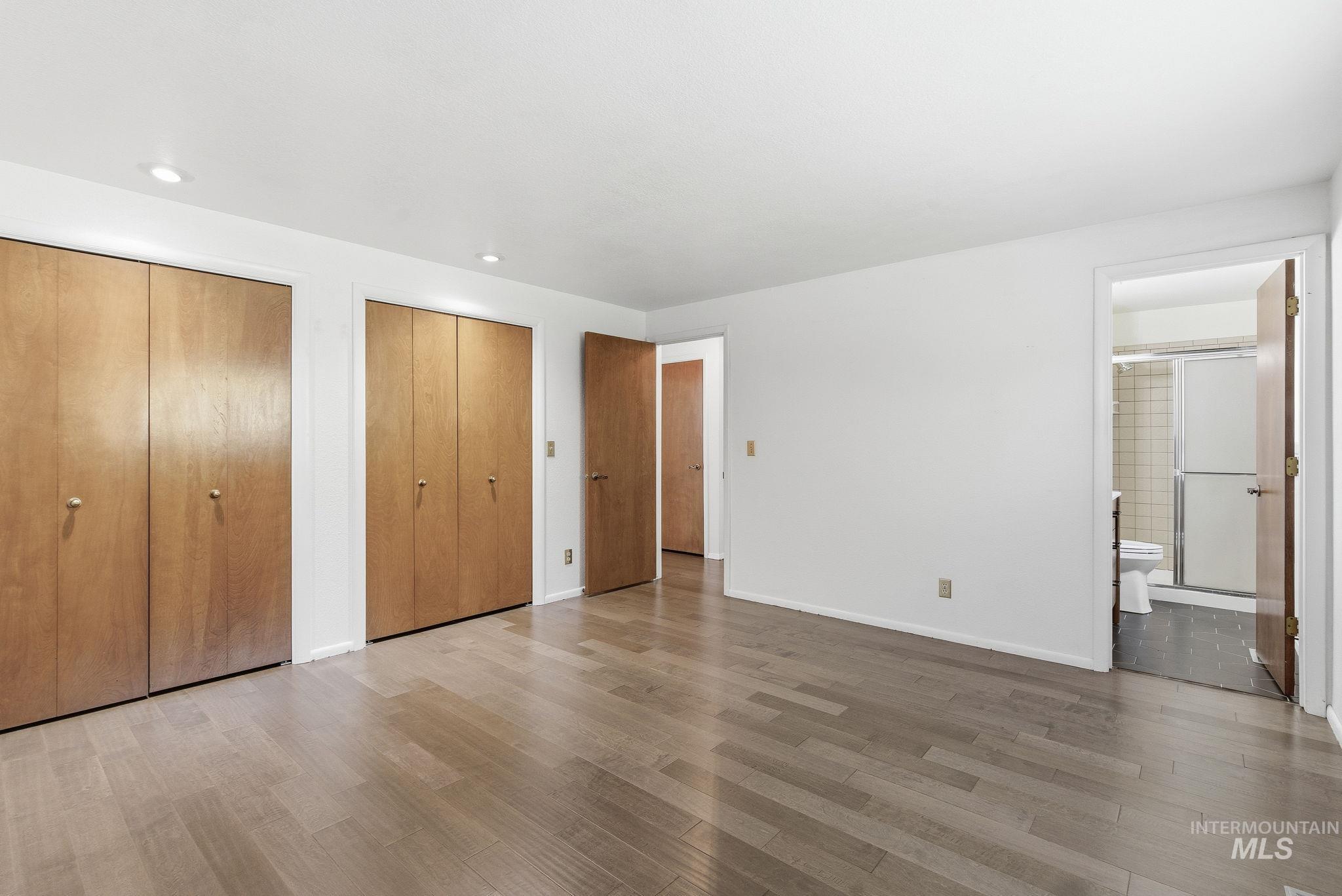 Unfurnished bedroom with multiple closets, light wood-style floors, ensuite bath, and recessed lighting