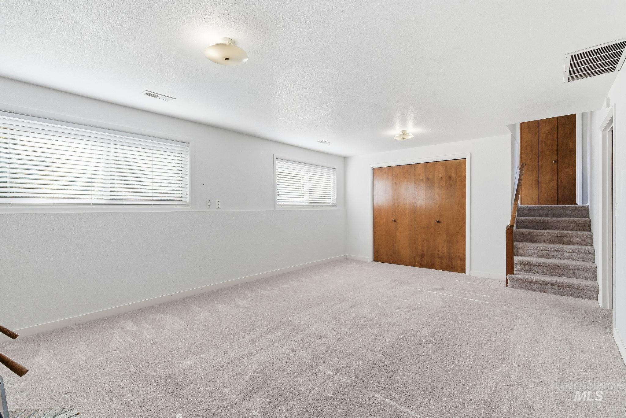 Spare room featuring carpet floors, stairs, and a textured ceiling