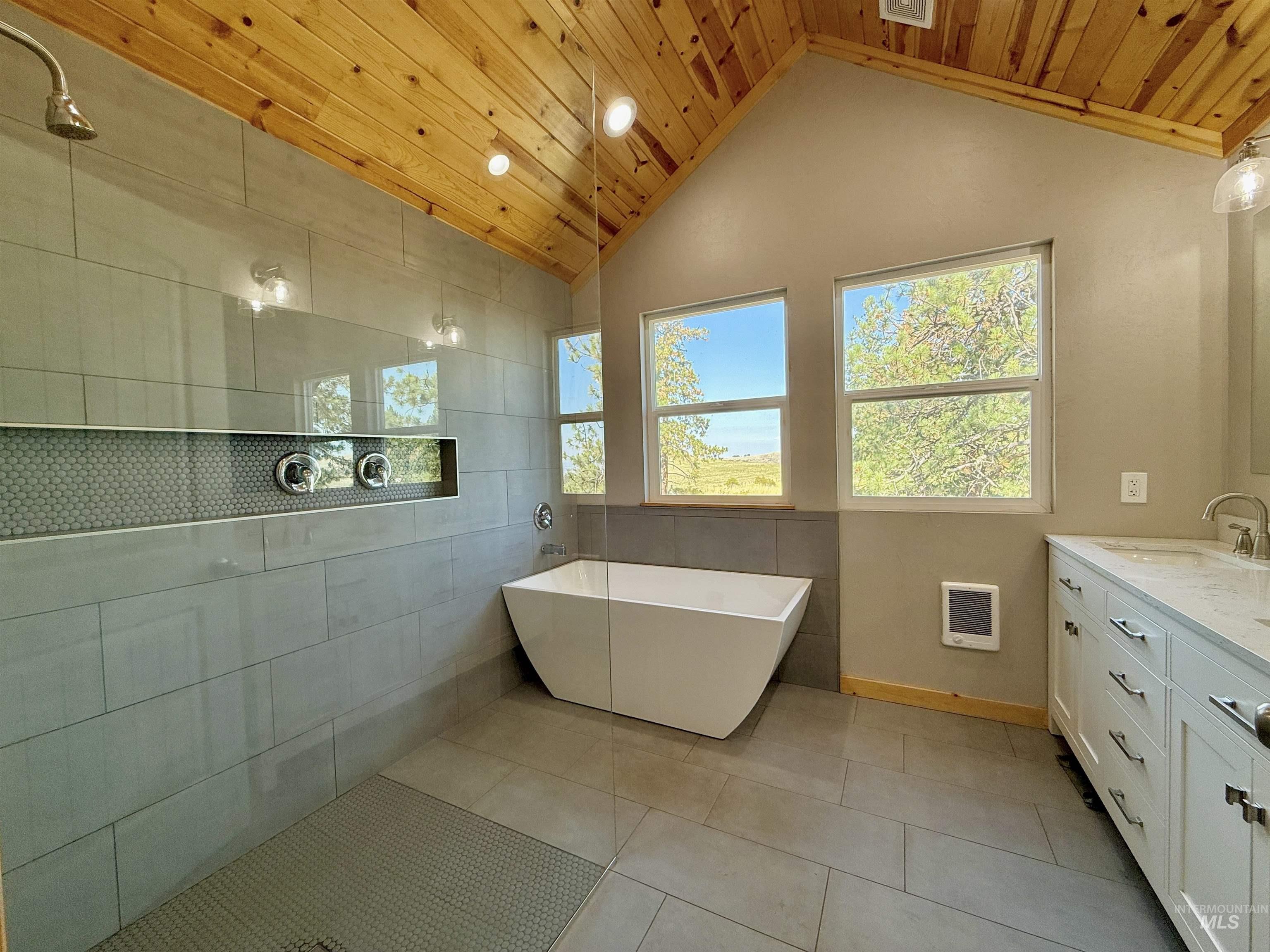 Bathroom with a freestanding tub, vanity, vaulted ceiling, wood ceiling, and light tile patterned flooring