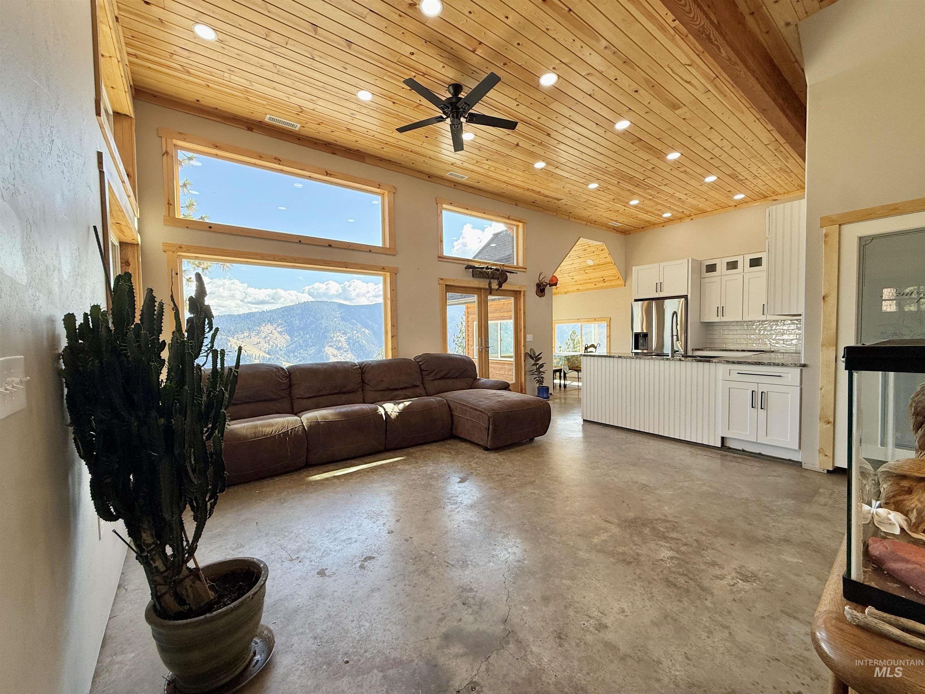 Living room with wood ceiling, concrete floors, recessed lighting, a towering ceiling, and a ceiling fan