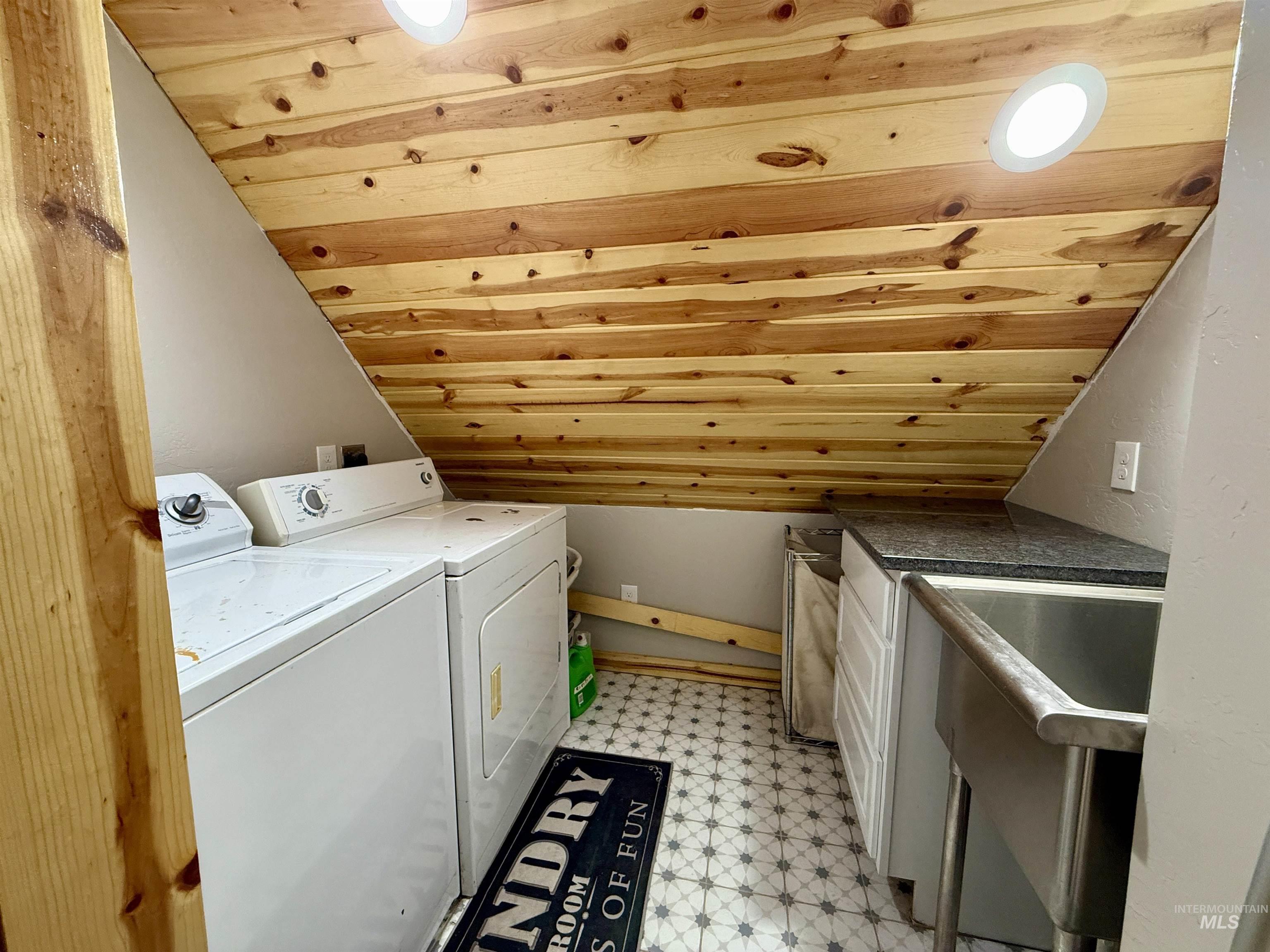 Washroom featuring wood ceiling, washing machine and clothes dryer, and light flooring