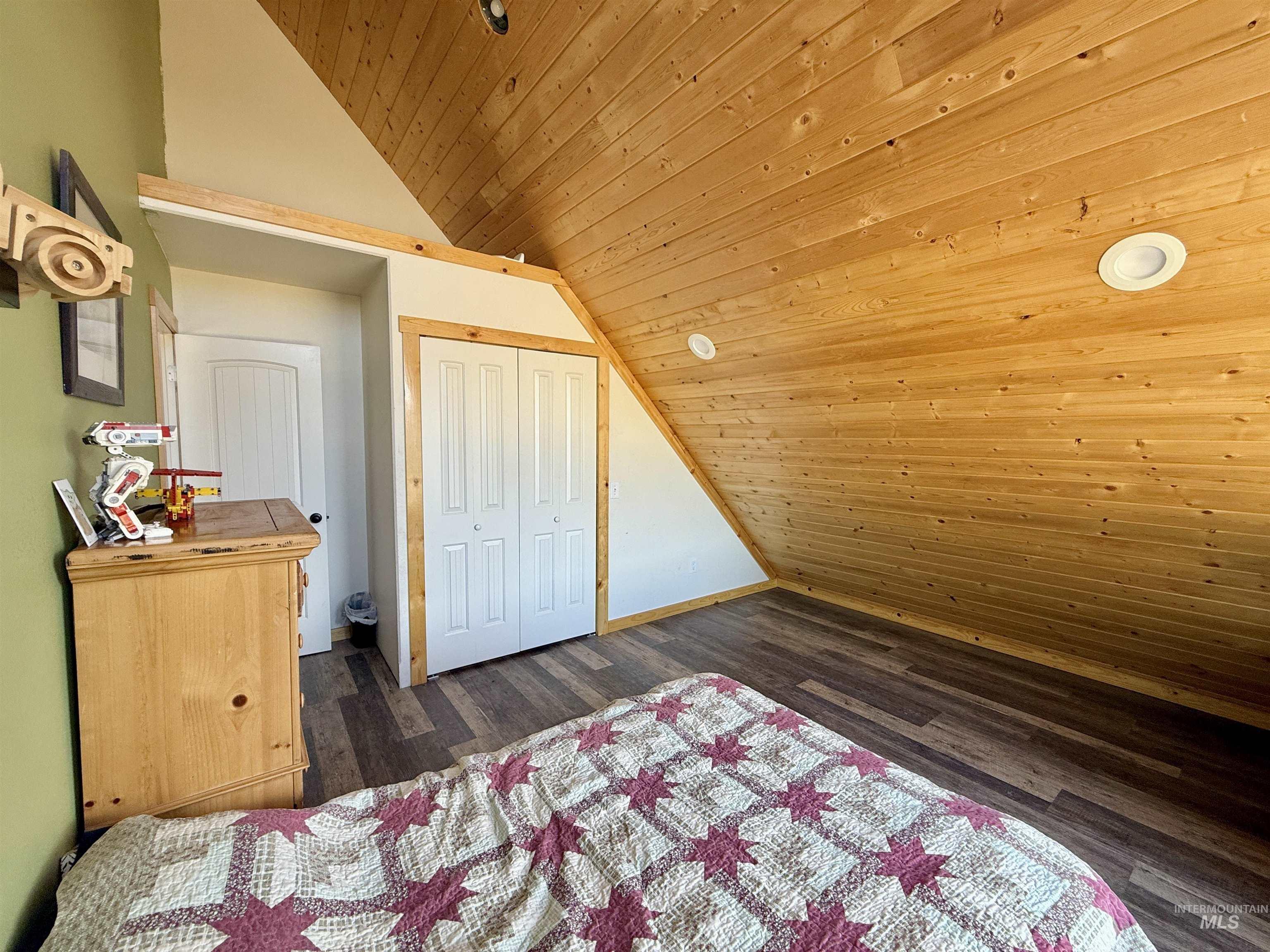 Bedroom featuring wooden ceiling, vaulted ceiling, dark wood-style floors, and a closet