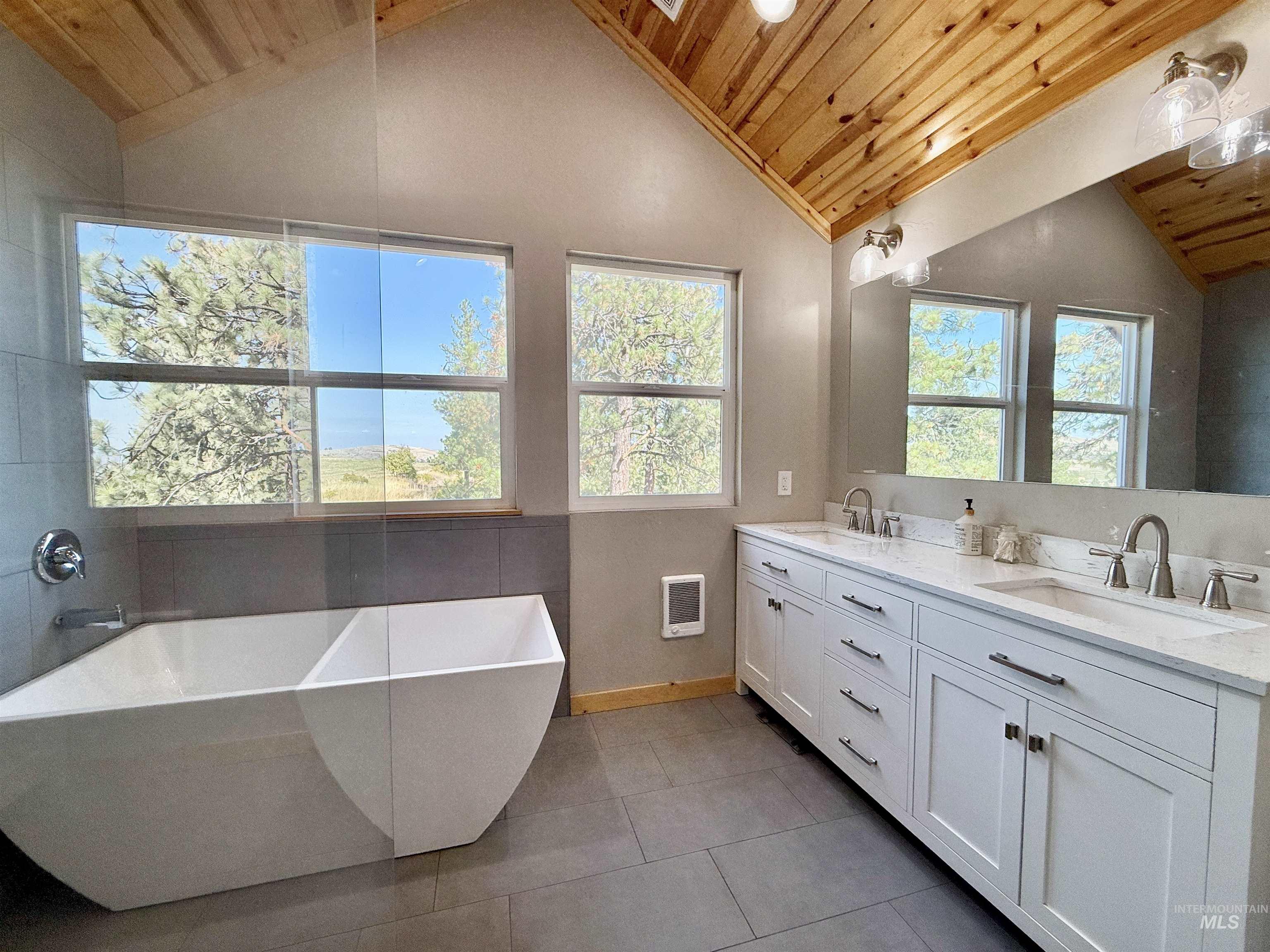 Full bath featuring lofted ceiling, a soaking tub, wood ceiling, double vanity, and light tile patterned floors