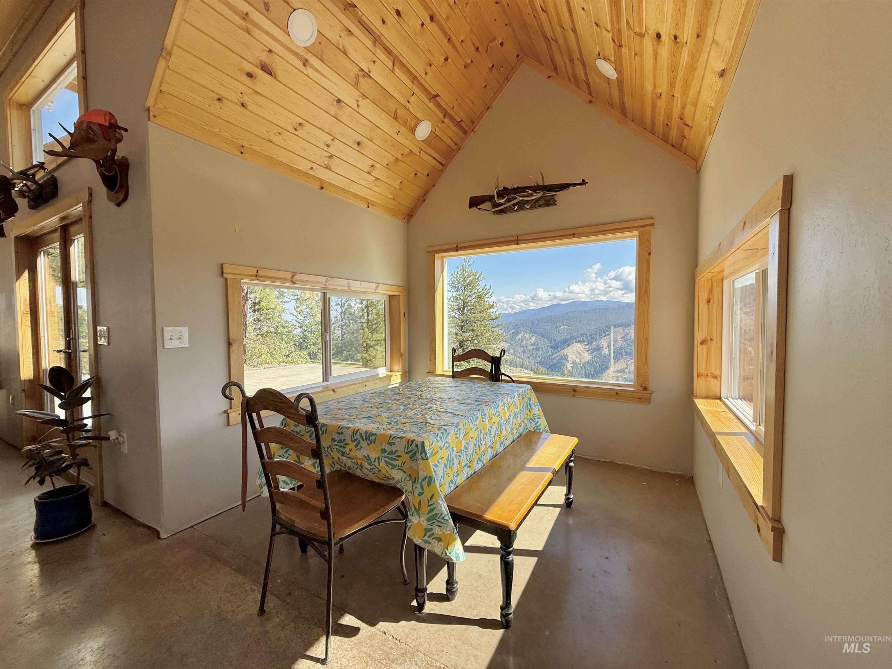 Dining area featuring high vaulted ceiling, plenty of natural light, wooden ceiling, and concrete floors