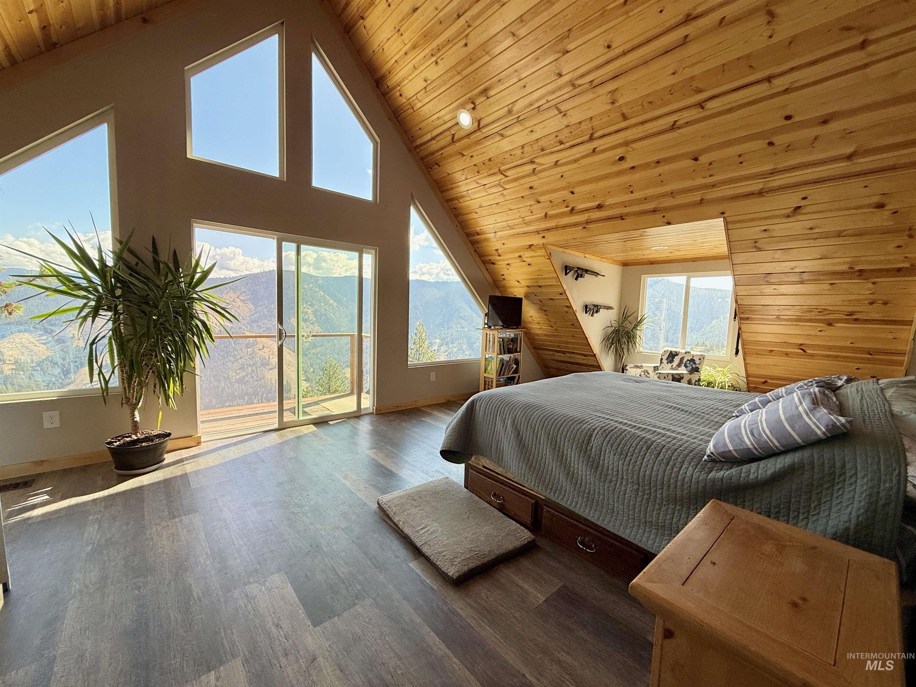 Bedroom featuring high vaulted ceiling, access to outside, wood ceiling, wood finished floors, and wooden walls