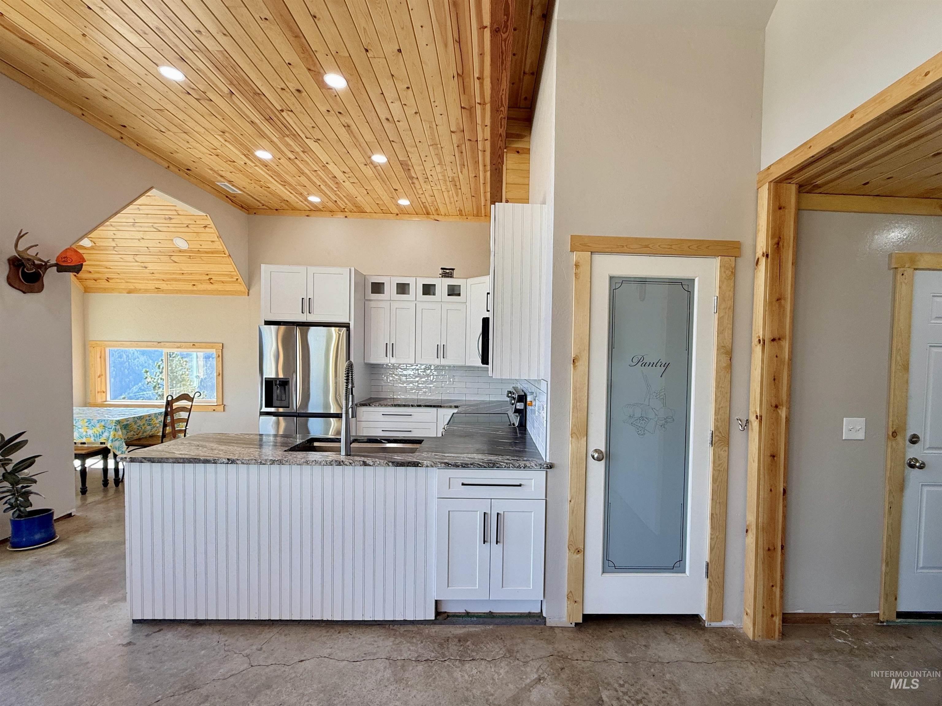 Kitchen featuring wood ceiling, white cabinets, dark stone counters, tasteful backsplash, and recessed lighting