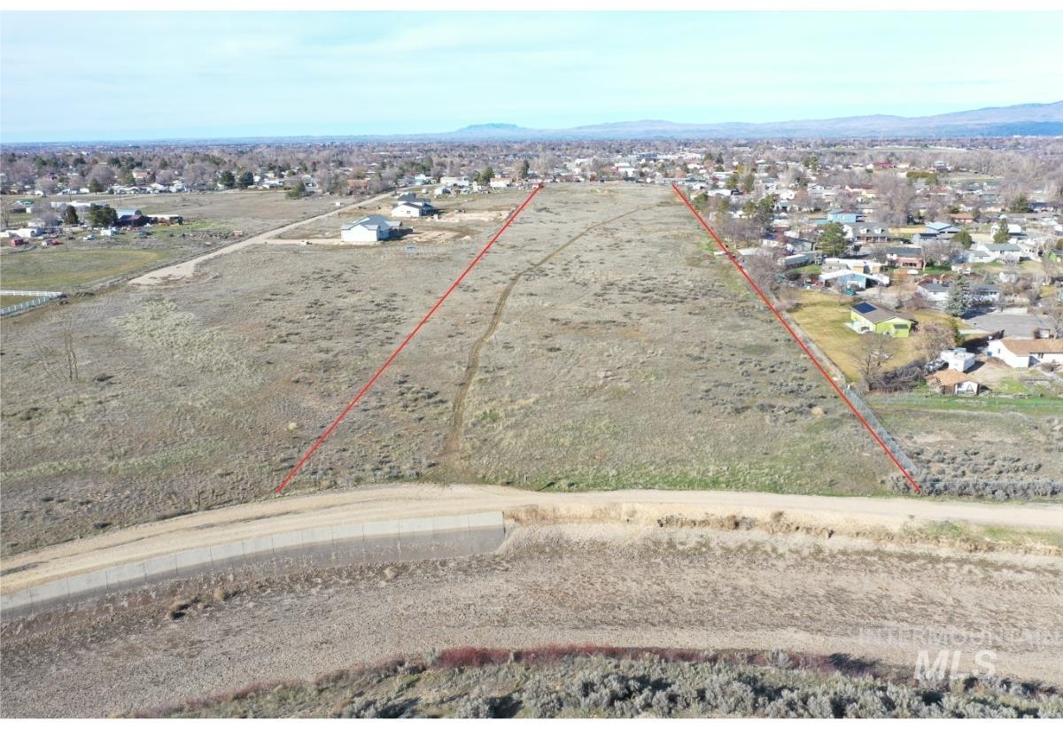 Aerial view of residential area featuring property boundaries highlighted and a mountain backdrop