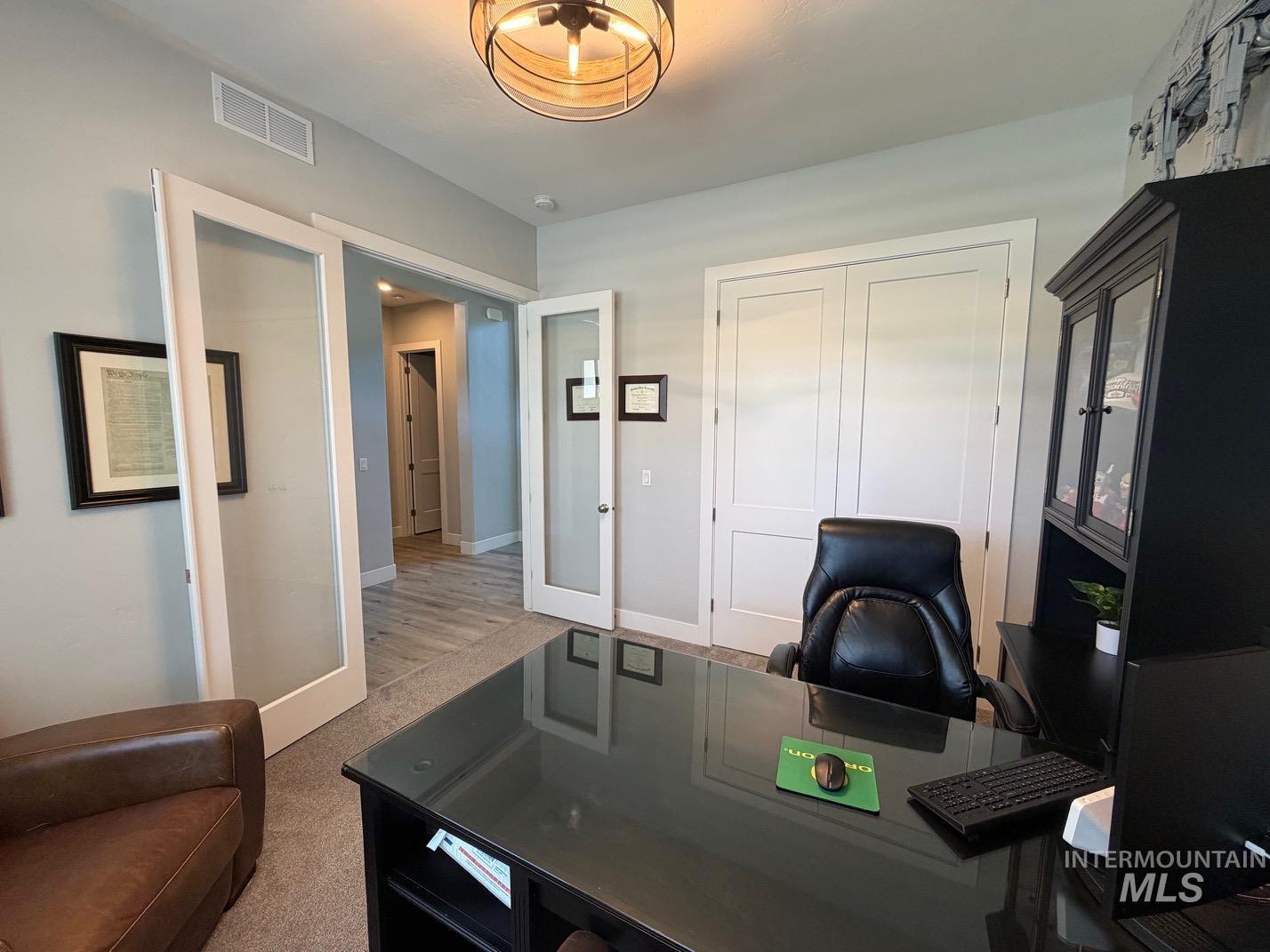 Interior room featuring double glass-panel doors, neutral wall tones, and recessed lighting