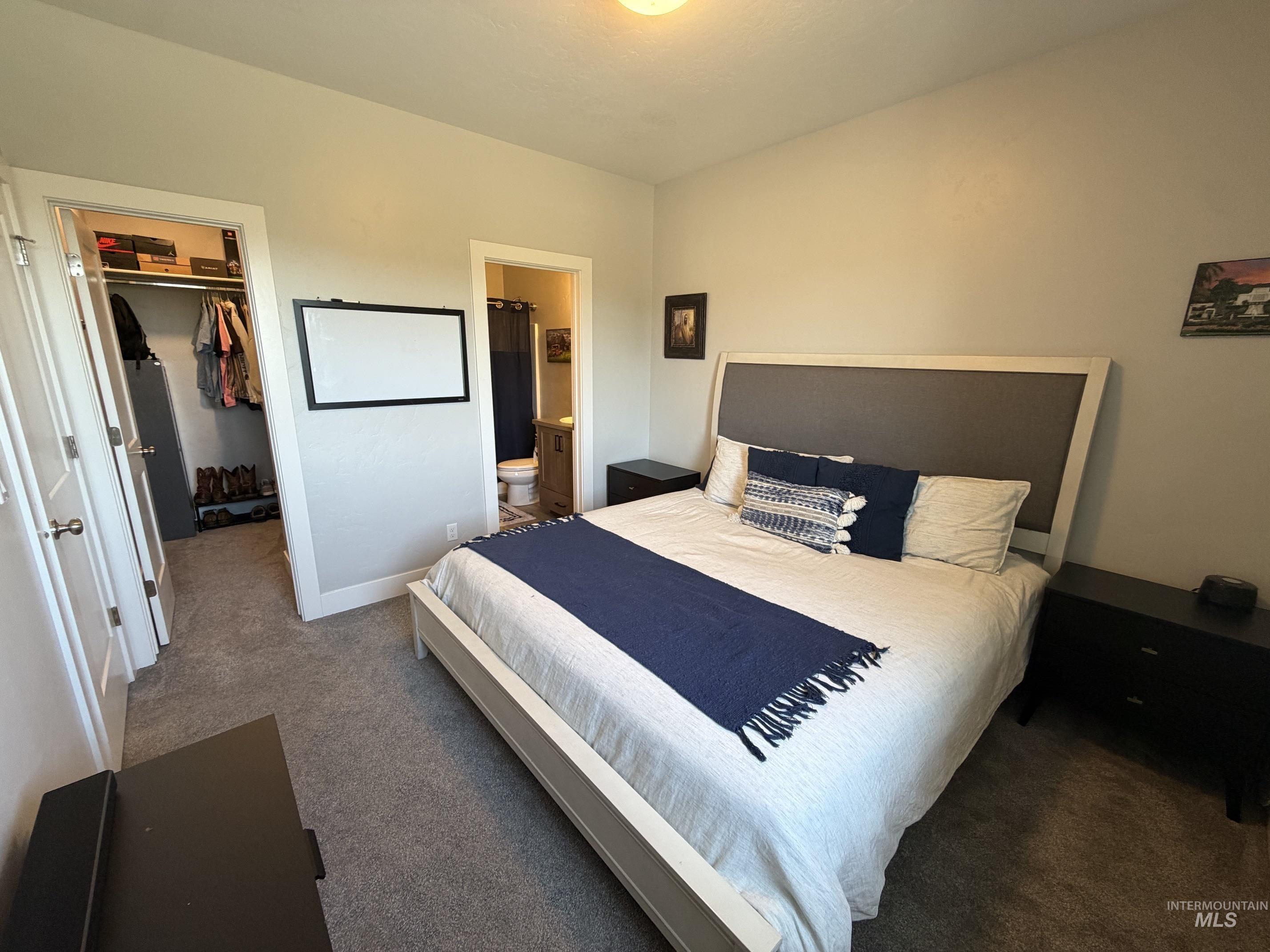 Carpeted bedroom featuring neutral wall tones, a built-in closet with shelving, and an en-suite bathroom access
