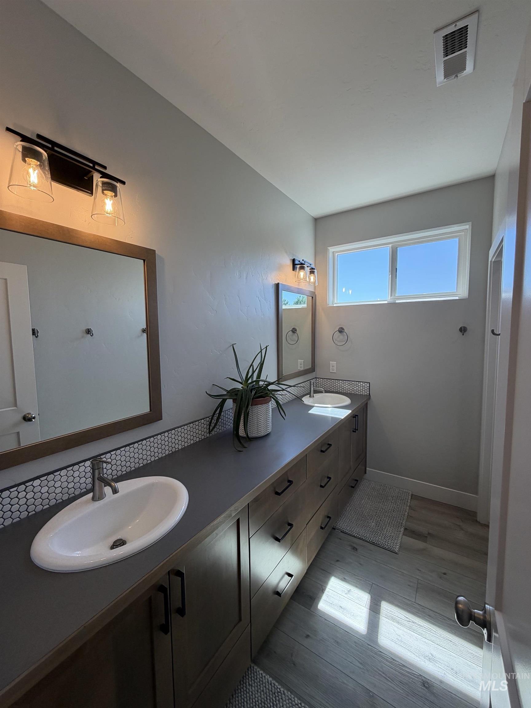 Extended vanity with dual undermount sinks, dark countertops, and wood-finish cabinetry