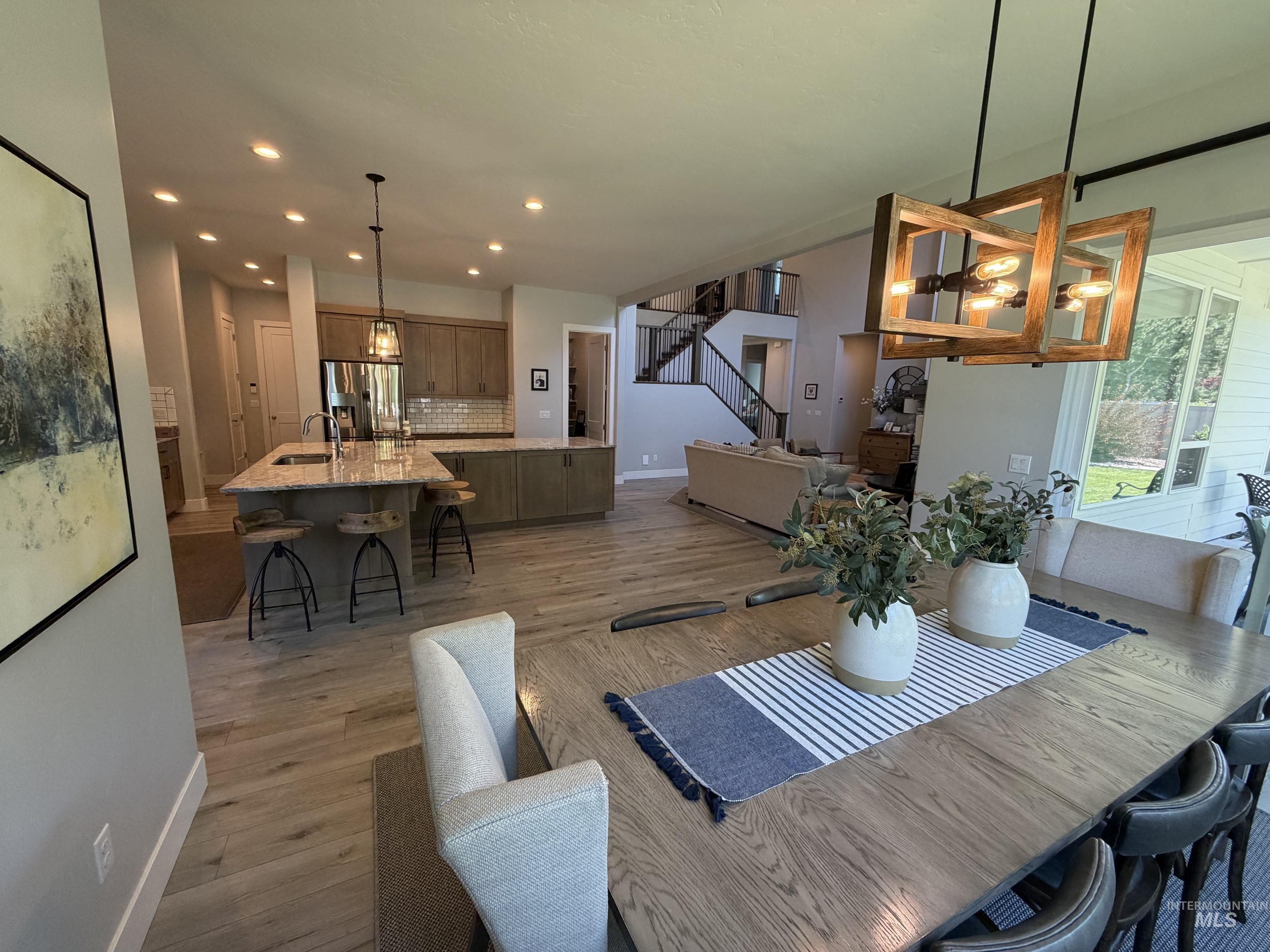 Open-concept living area featuring wood-finish flooring, recessed lighting, and a modern kitchen with a large island and stainless steel appliances