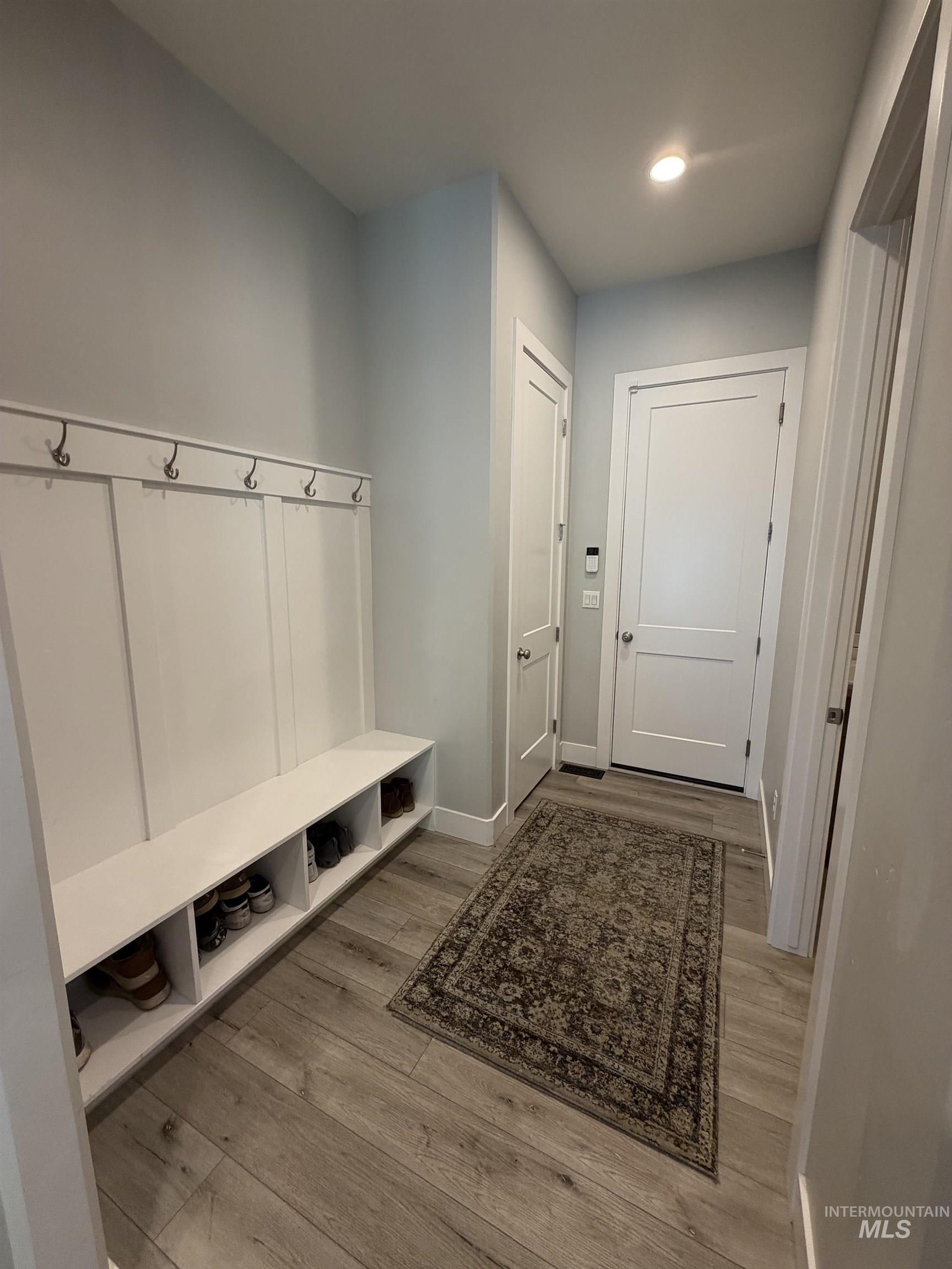 Entryway featuring a built-in bench with integrated shelving and wall-mounted hooks